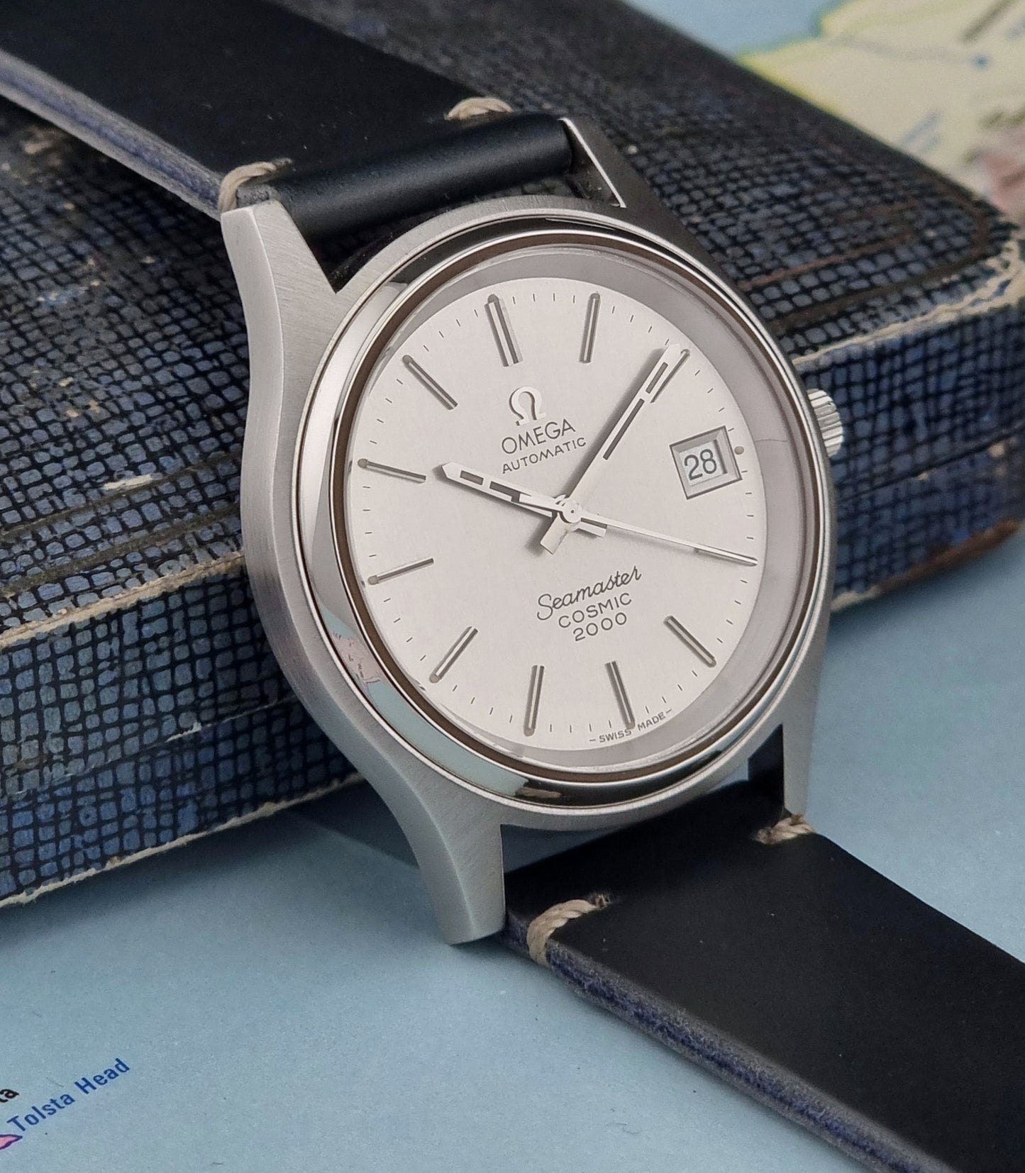 Omega Seamaster Cosmic 2000 166.128 watch with black strap on a textured surface