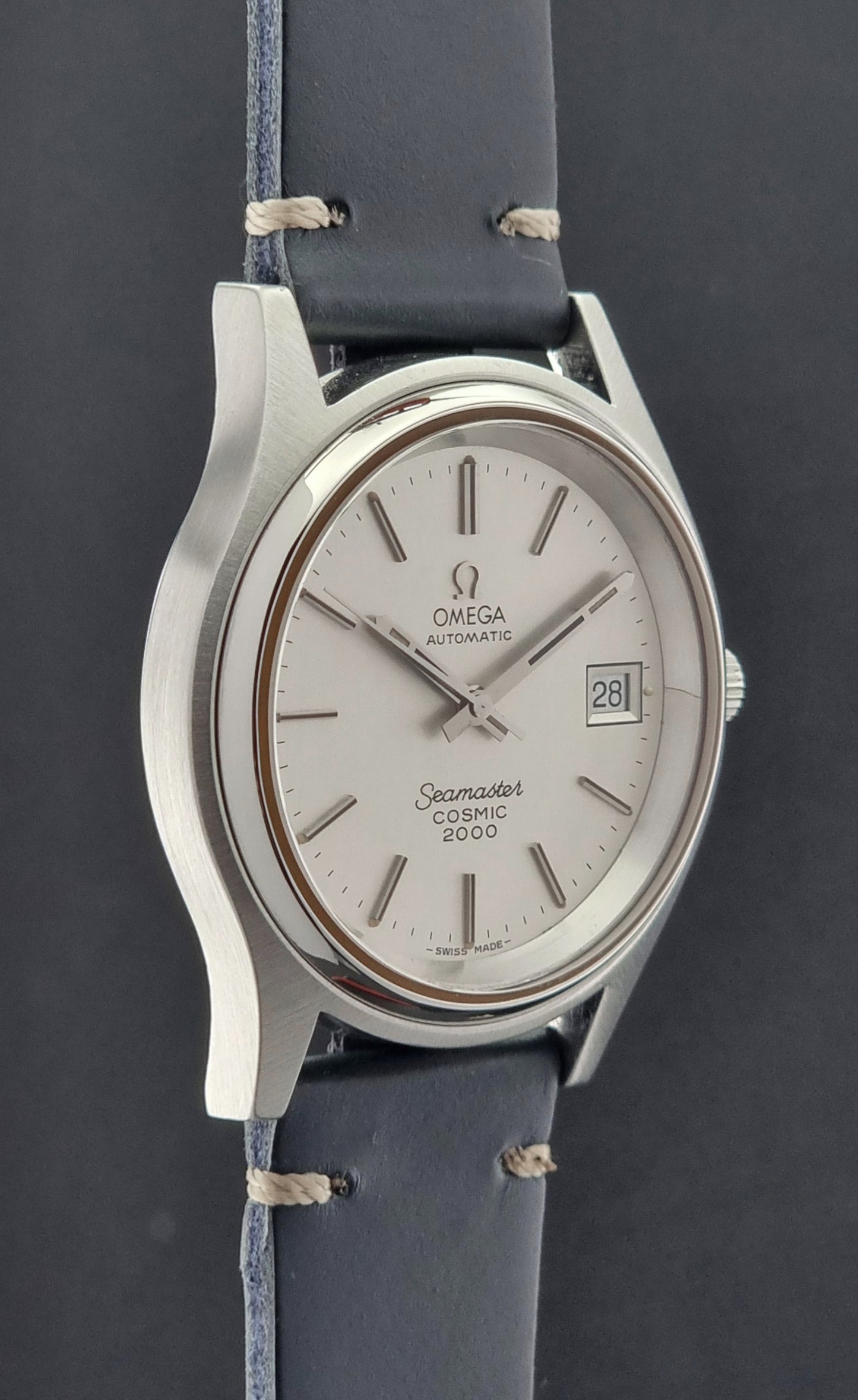 Omega Seamaster Cosmic 2000 166.128 watch with silver case and blue leather strap on a dark background
