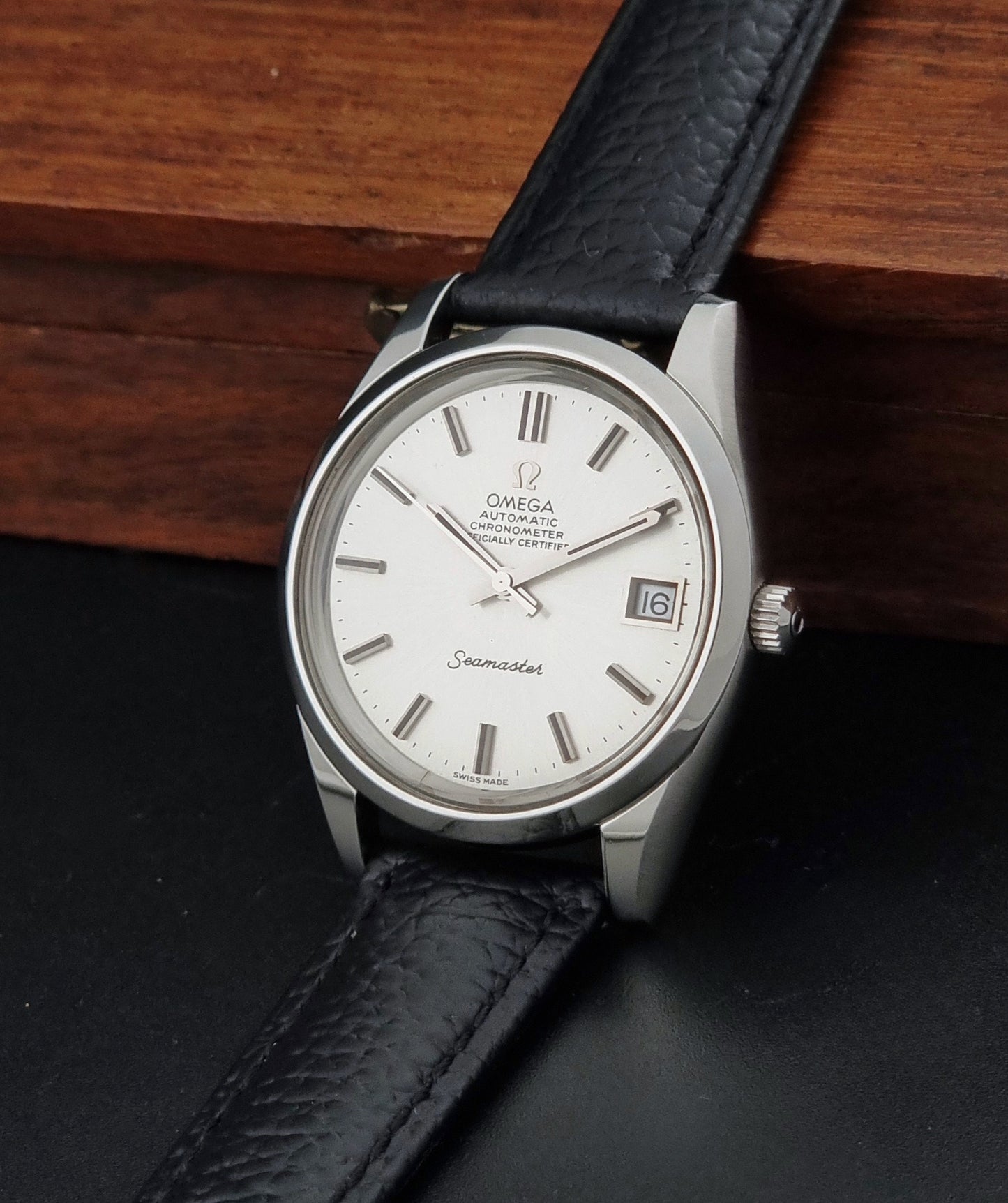 Vintage Omega Seamaster 168.0061/166.0172 with a silver stainless steel case and a textured black leather strap, shown on a dark background crown view