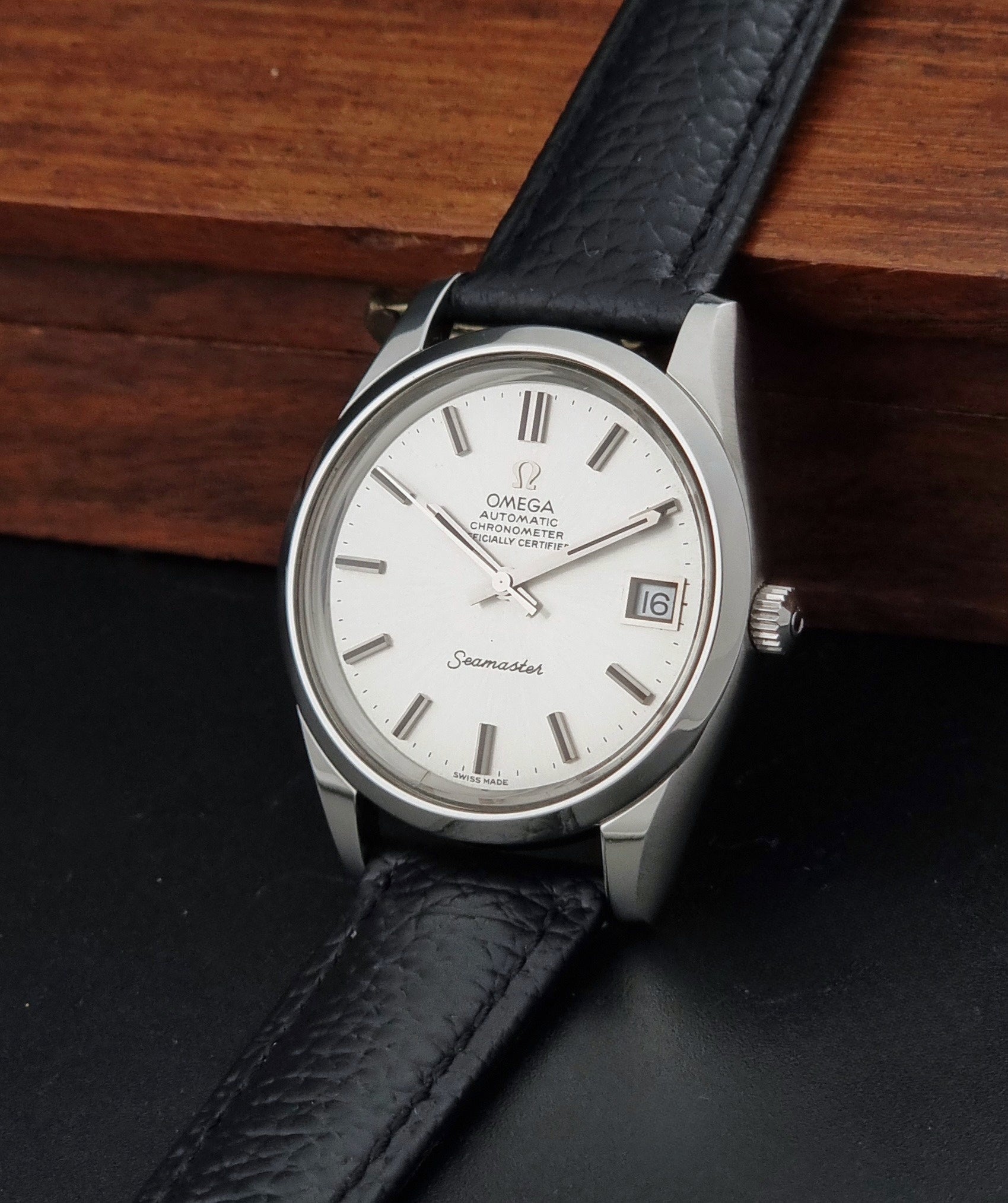Vintage Omega Seamaster 168.0061/166.0172 with a silver stainless steel case and a textured black leather strap, shown on a dark background crown view