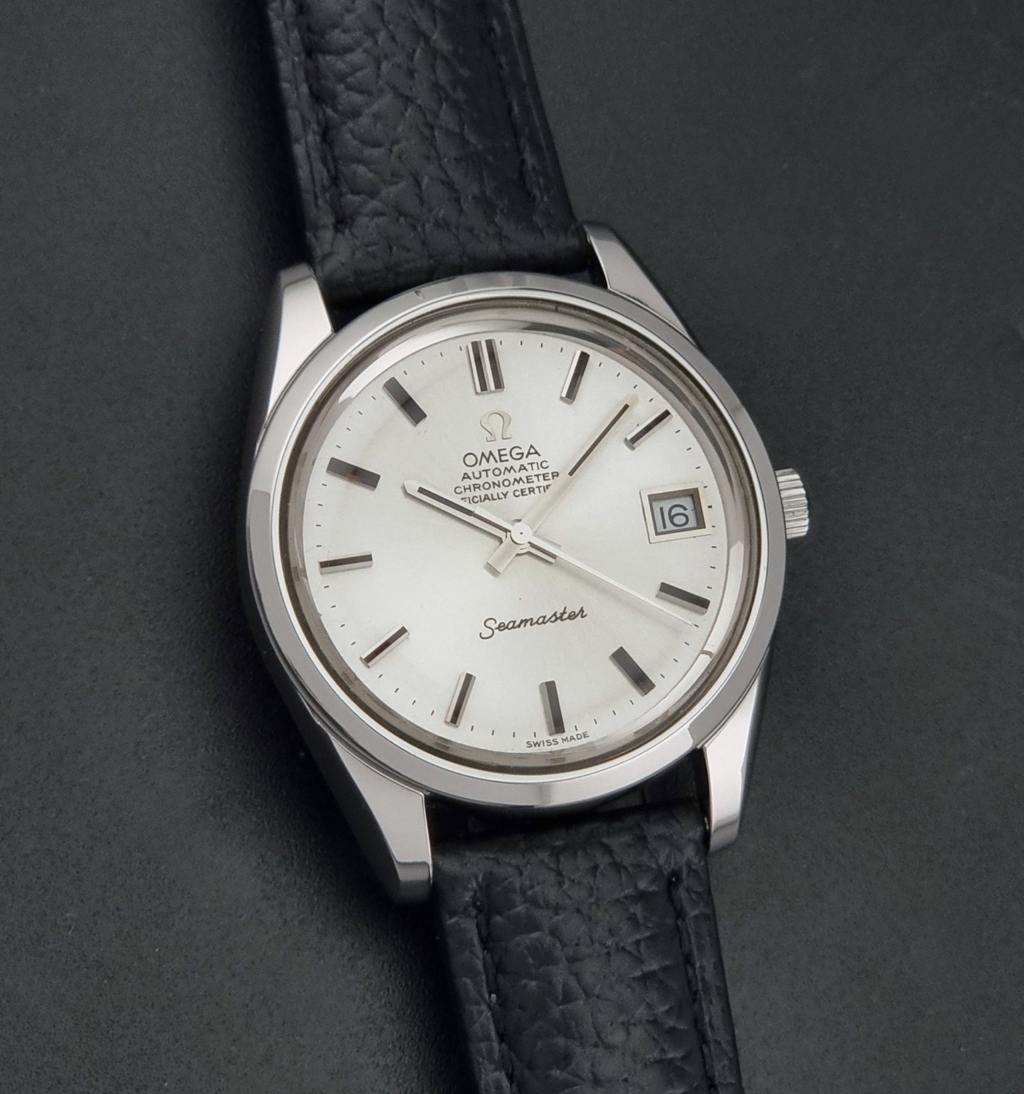 Vintage Omega Seamaster 168.0061/166.0172 with a silver stainless steel case and a textured black leather strap, shown on a dark background front view