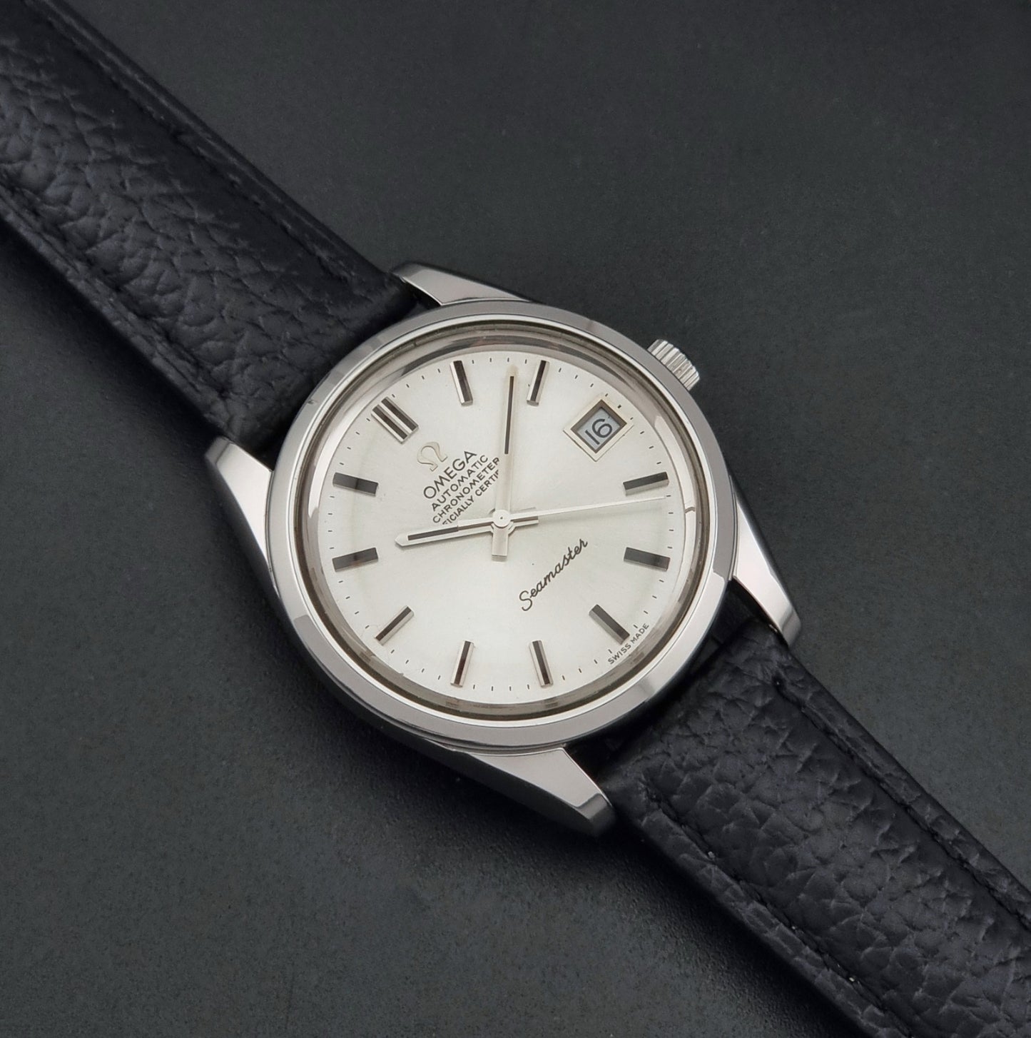 Vintage Omega Seamaster 168.0061/166.0172 with a silver stainless steel case and a textured black leather strap, shown on a dark background dial
