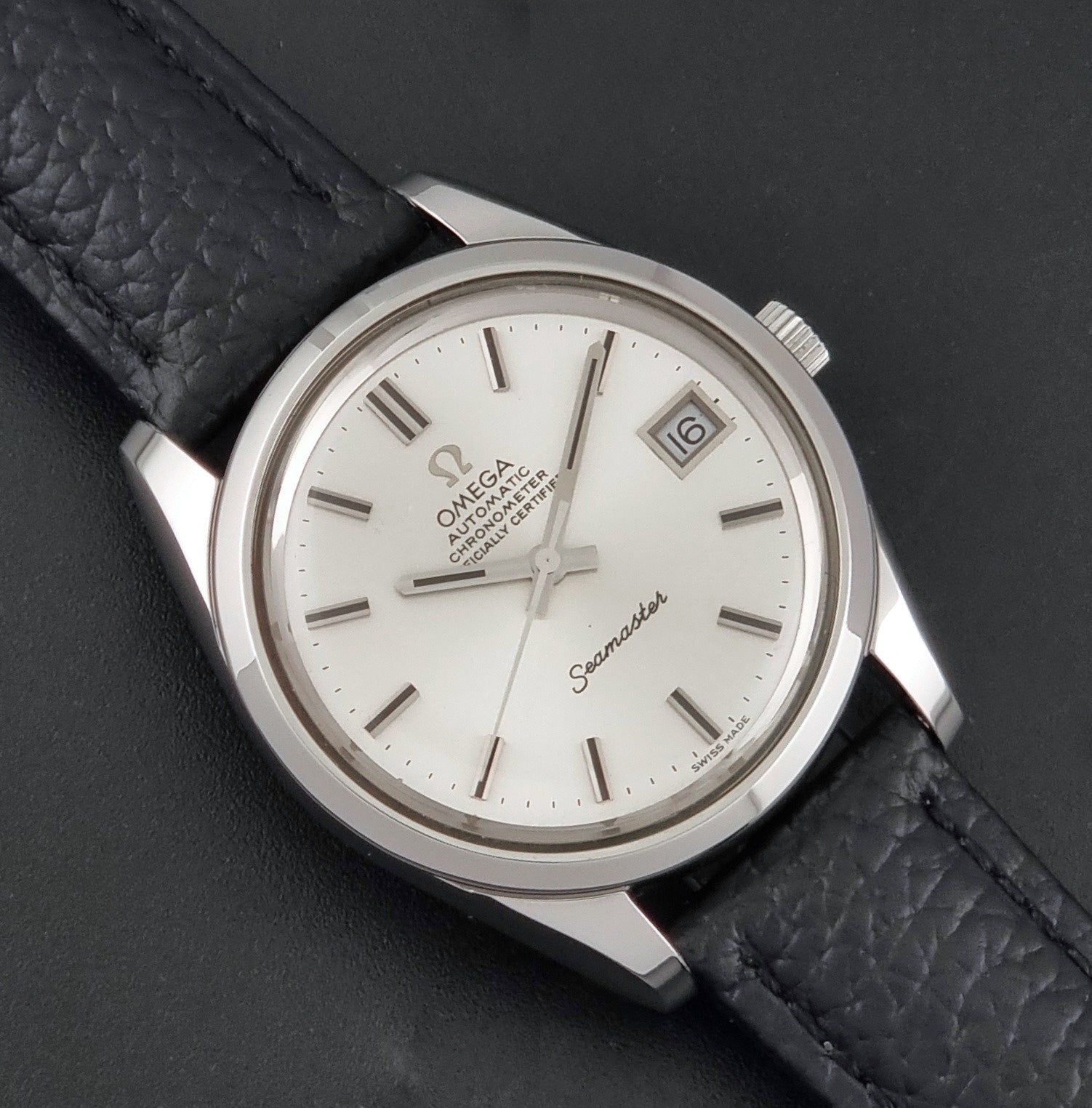 Vintage Omega Seamaster 168.0061/166.0172 with a silver stainless steel case and a textured black leather strap, shown on a dark background close up dial view