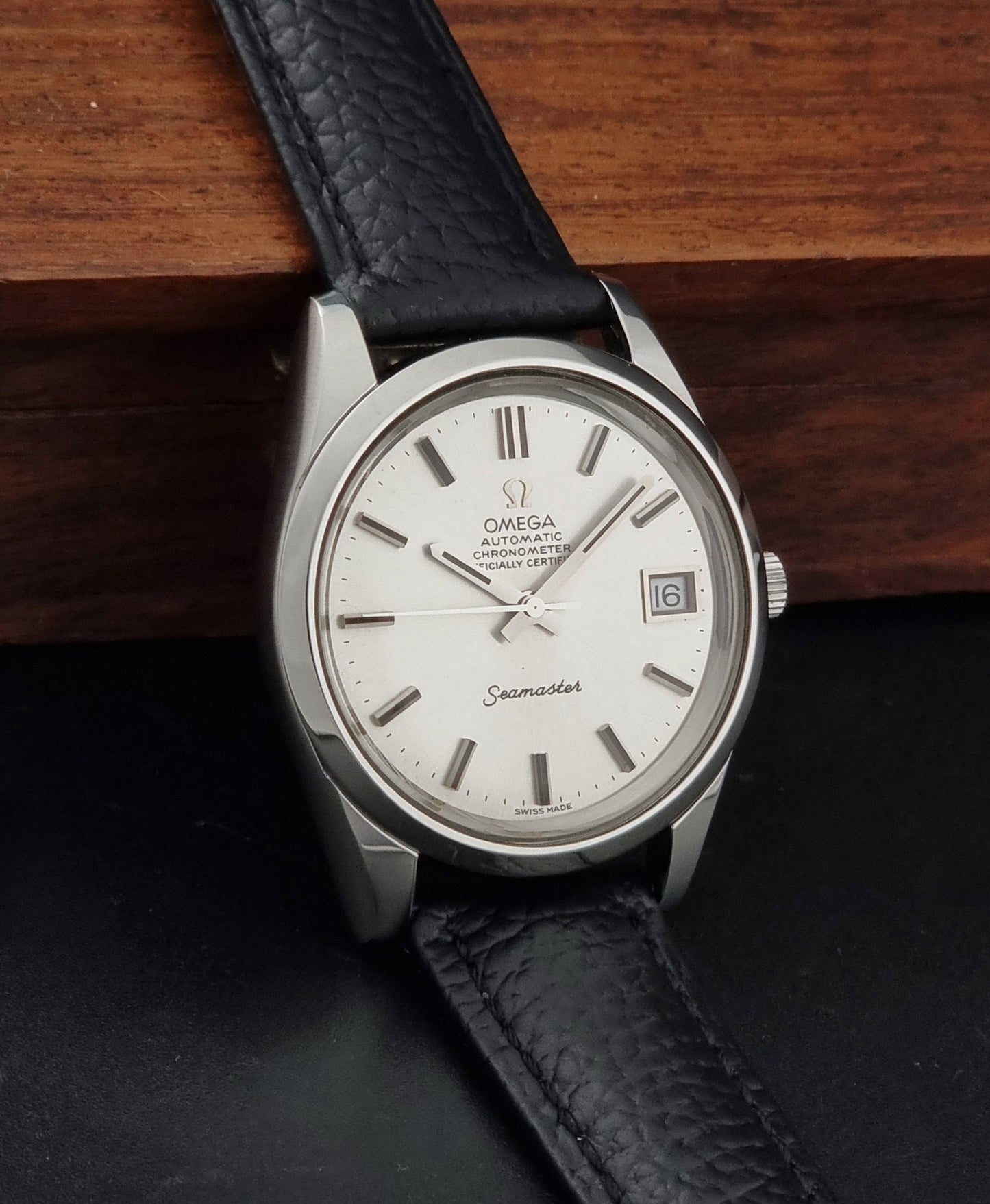 Vintage Omega Seamaster 168.0061/166.0172 with a silver stainless steel case and a textured black leather strap, shown on a dark background side view