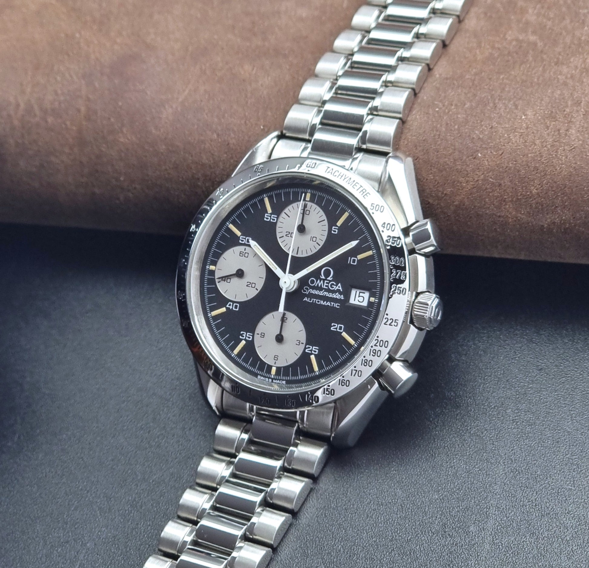Vintage Omega Speedmaster watch 3511.50  Reverse Panda Date Chronograph with a black face on a dark background crown view
