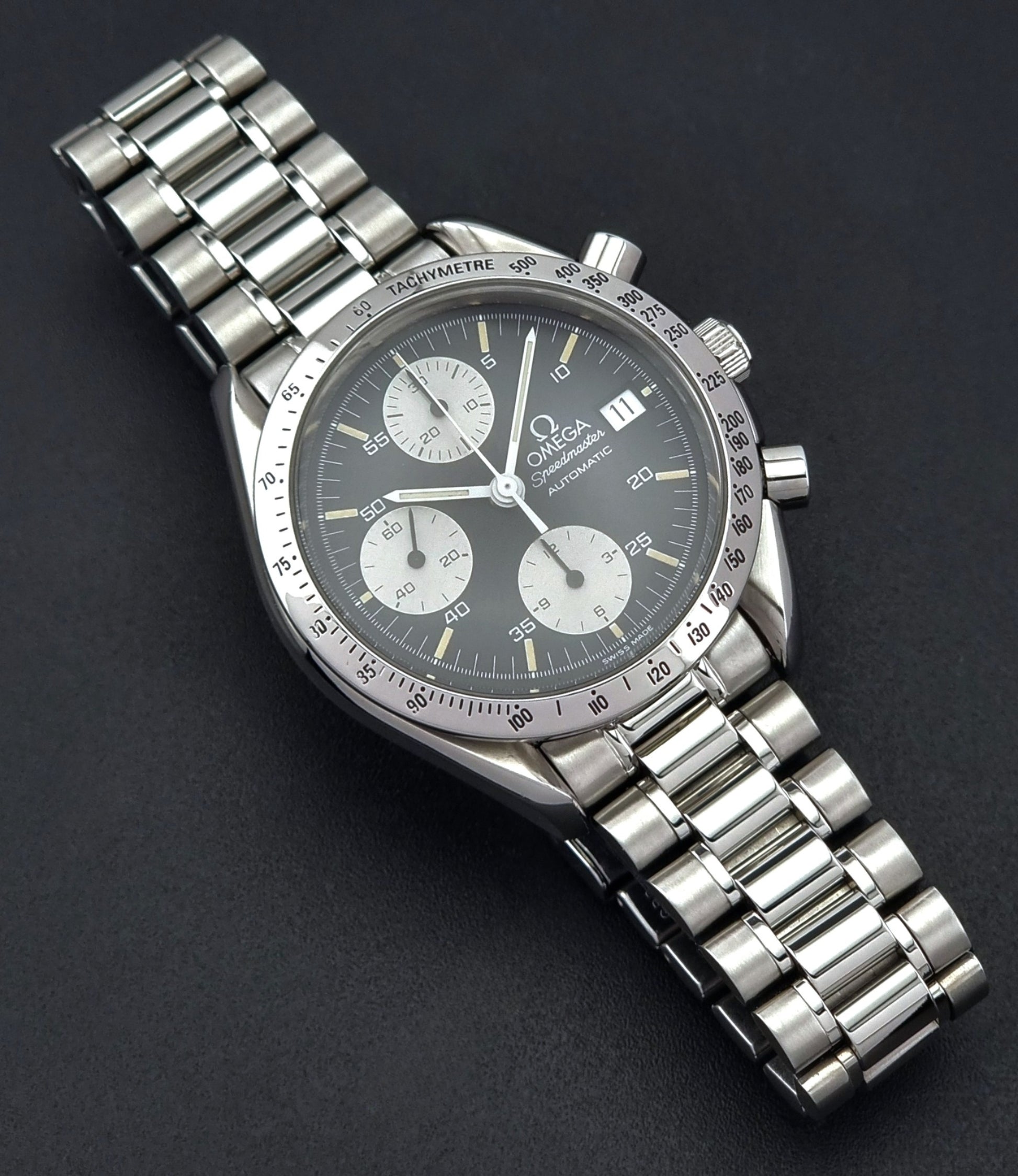 Vintage Omega Speedmaster watch 3511.50  Reverse Panda Date Chronograph with a black face on a dark background white sub dials