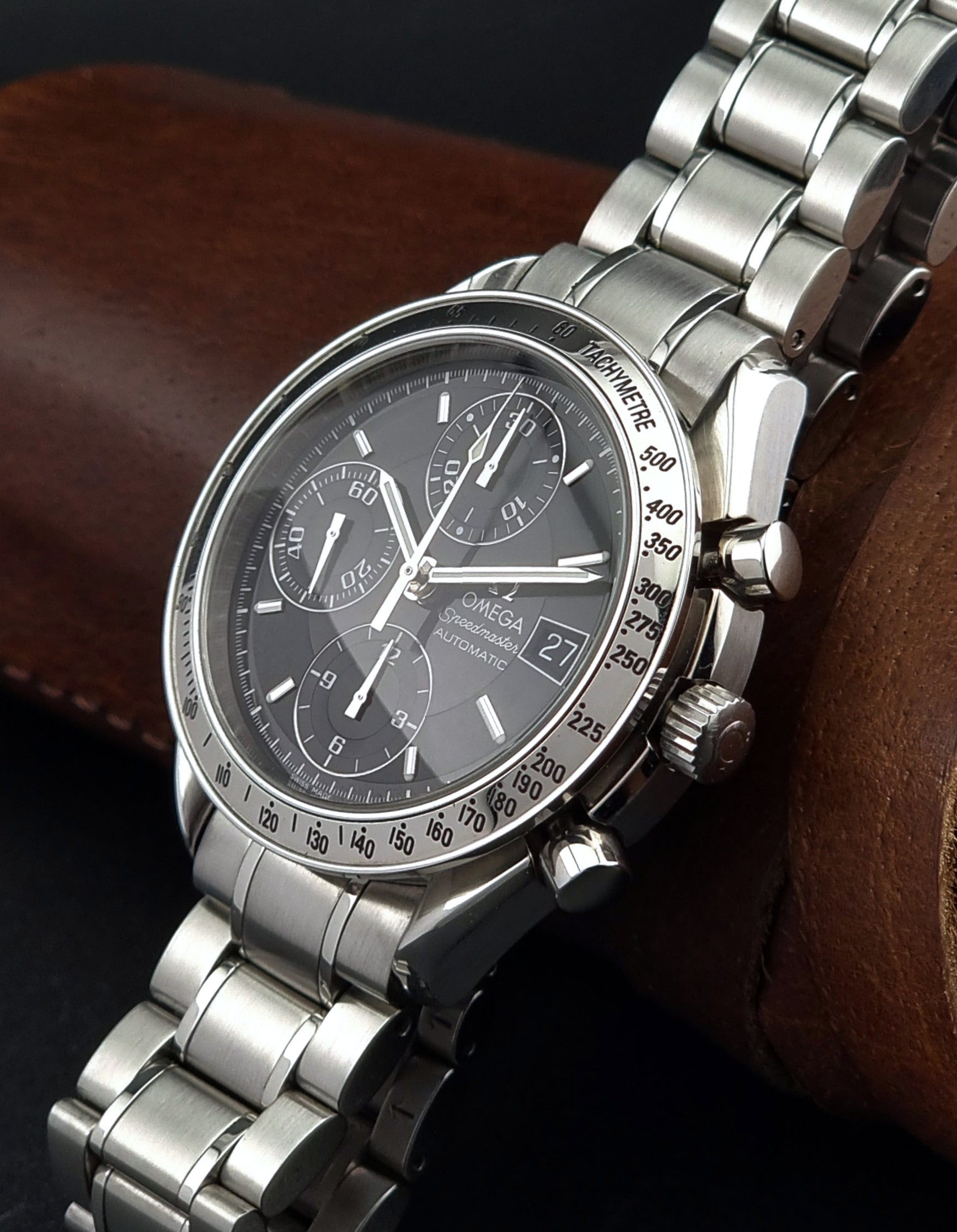 Omega Speedmaster watch with a detailed face on a brown leather surface
