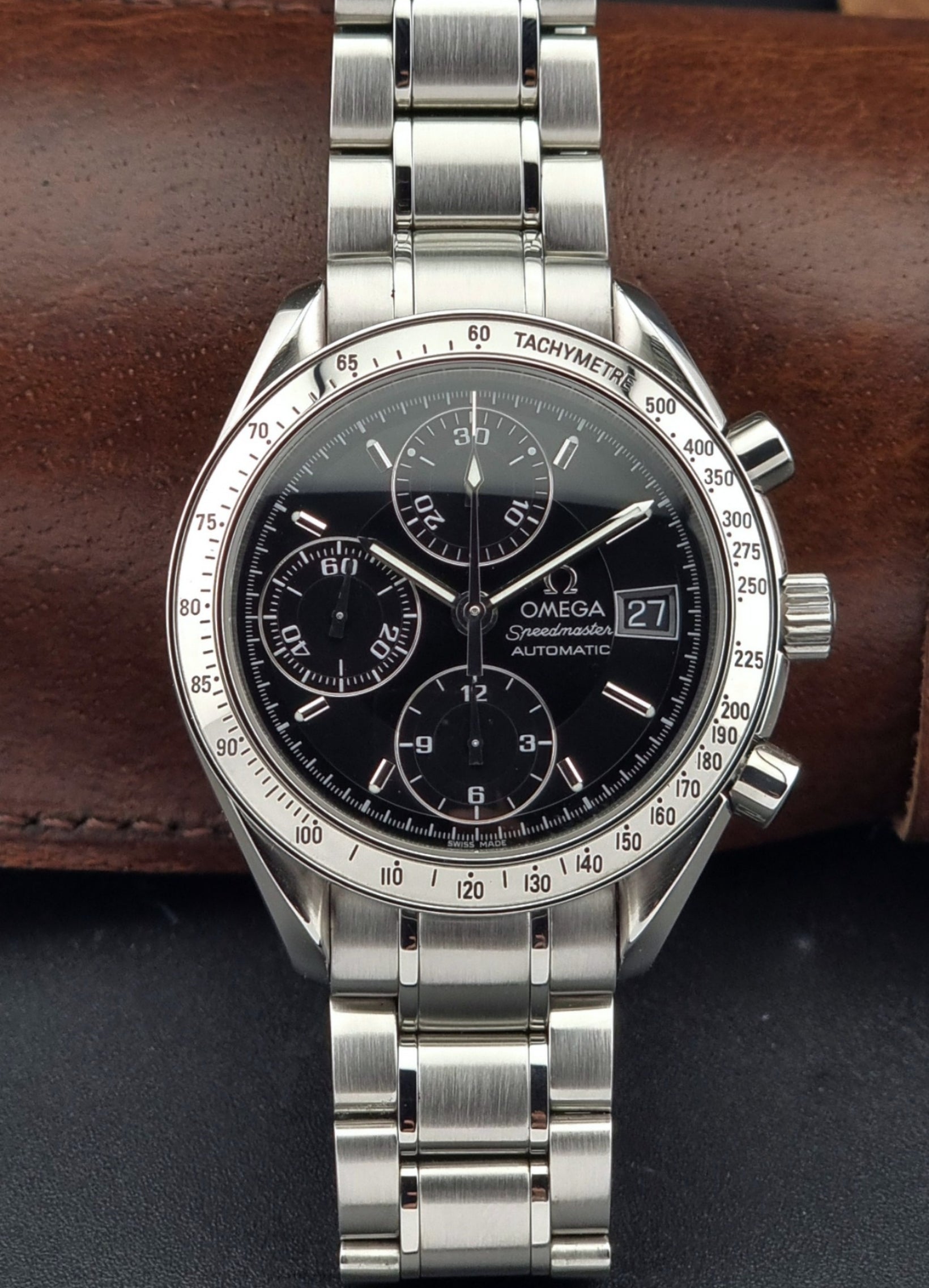 Omega Speedmaster watch with black dial on a brown leather strap
