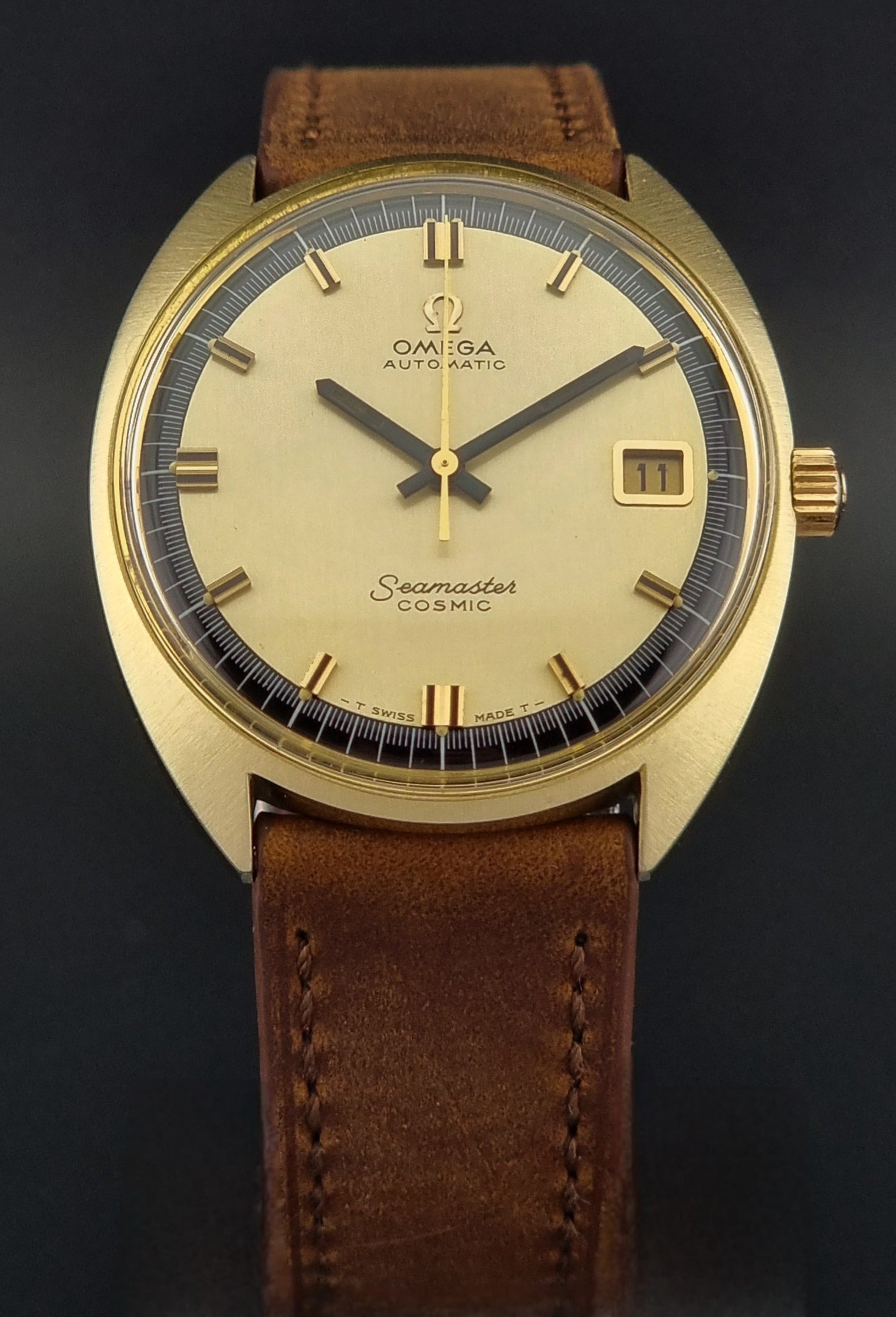 Gold watch with a brown leather strap on a black background