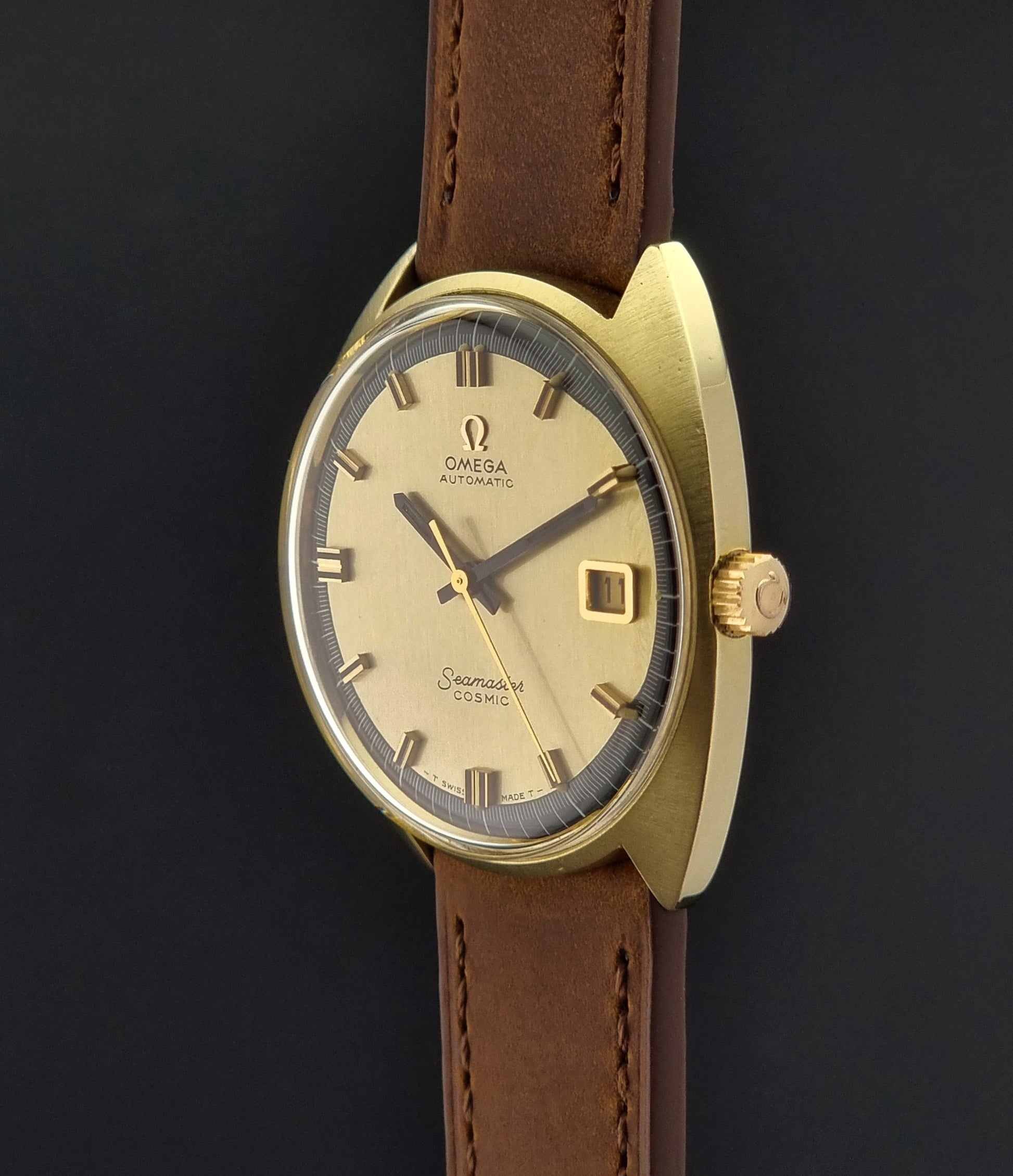 Gold watch with brown leather strap on a black background