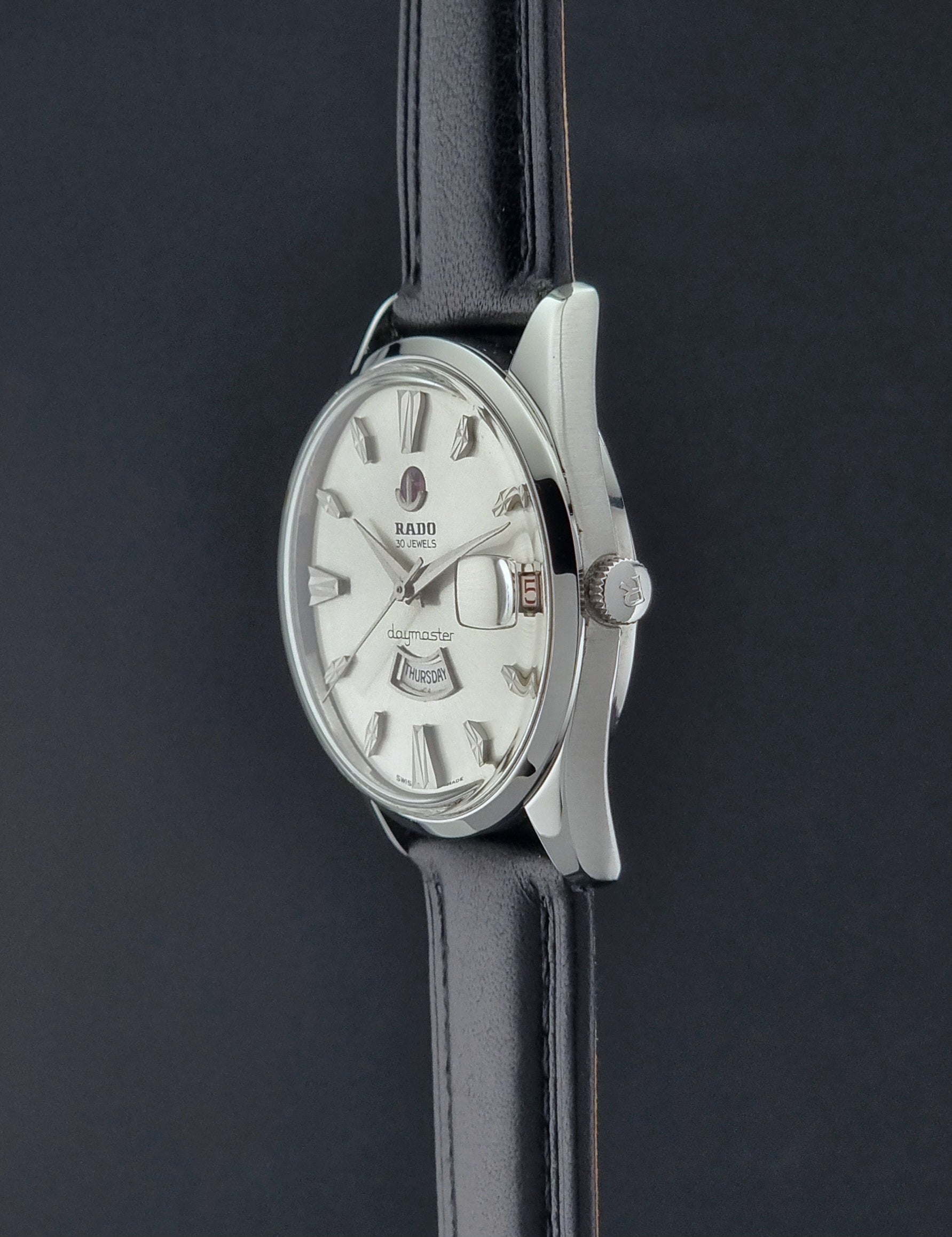 Vintage Rado wristwatch Daymaster 11754 with black leather strap on a dark surface crown profile view