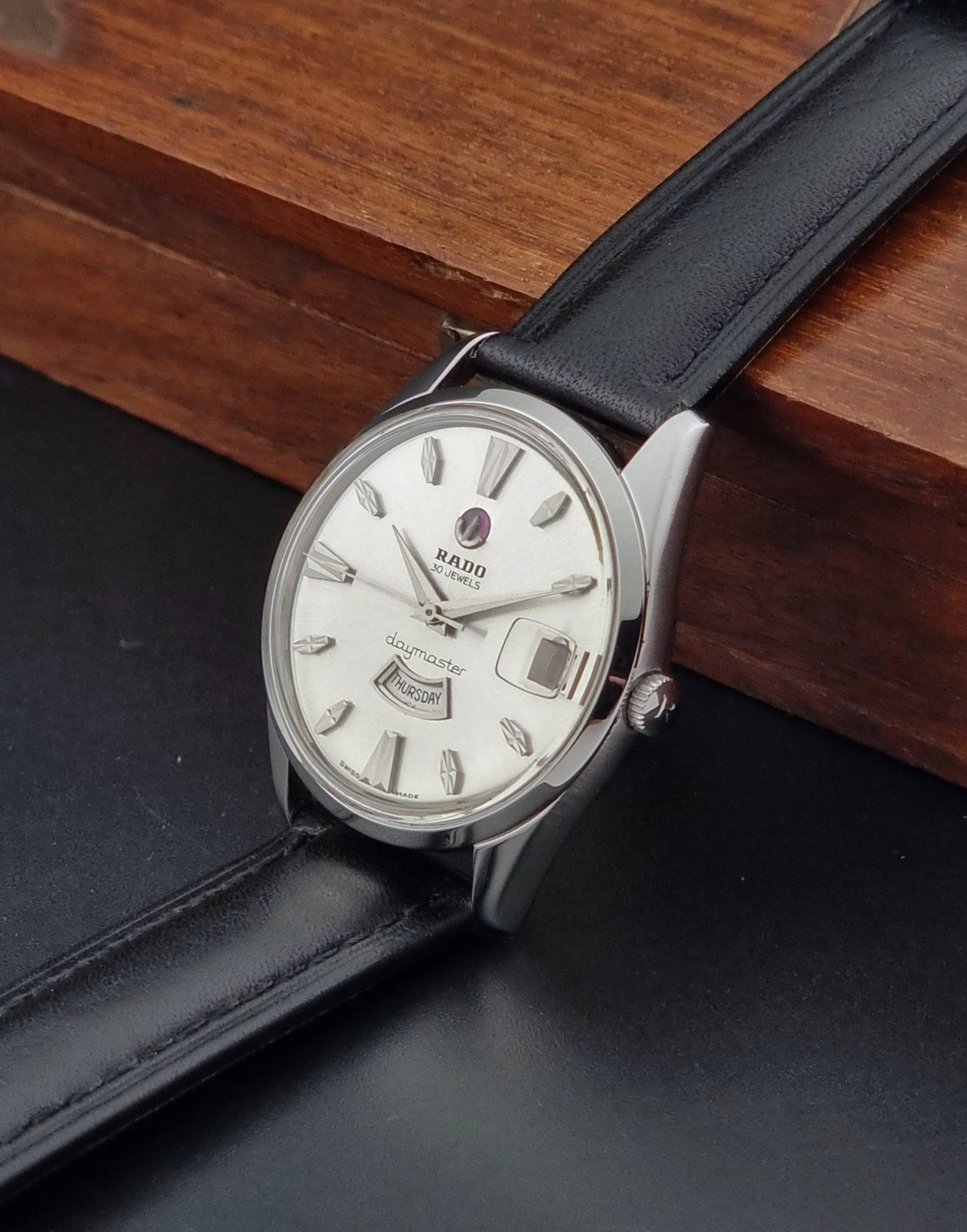 Vintage Rado wristwatch Daymaster 11754 with black leather strap on a dark surface crown view