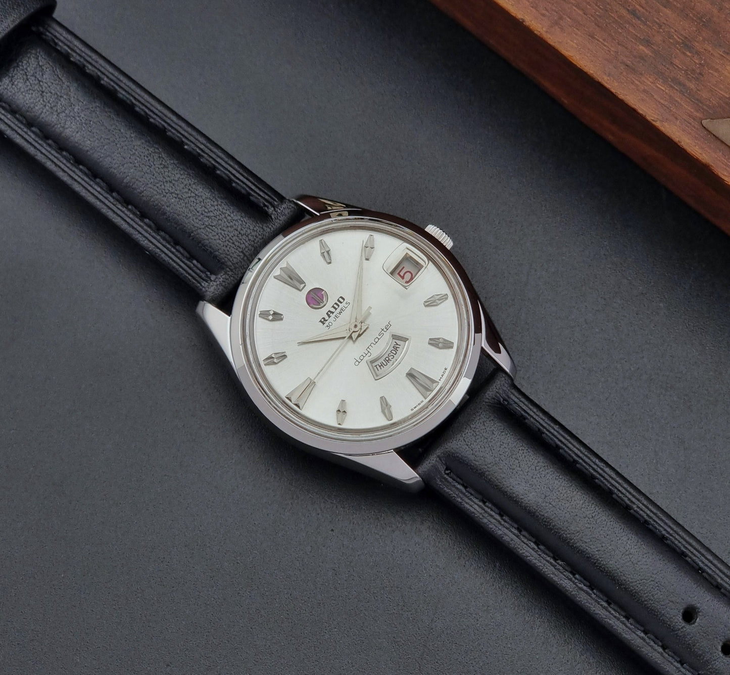 Vintage Rado wristwatch Daymaster 11754 with black leather strap on a dark surface dial