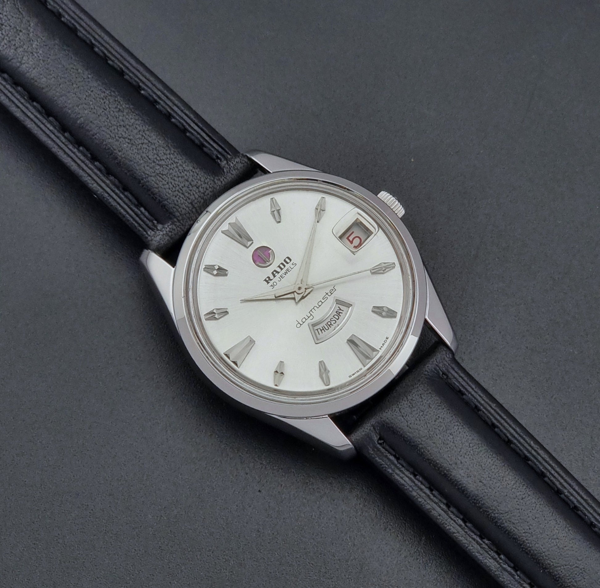 Vintage Rado wristwatch Daymaster 11754 with black leather strap on a dark surface close up dial view