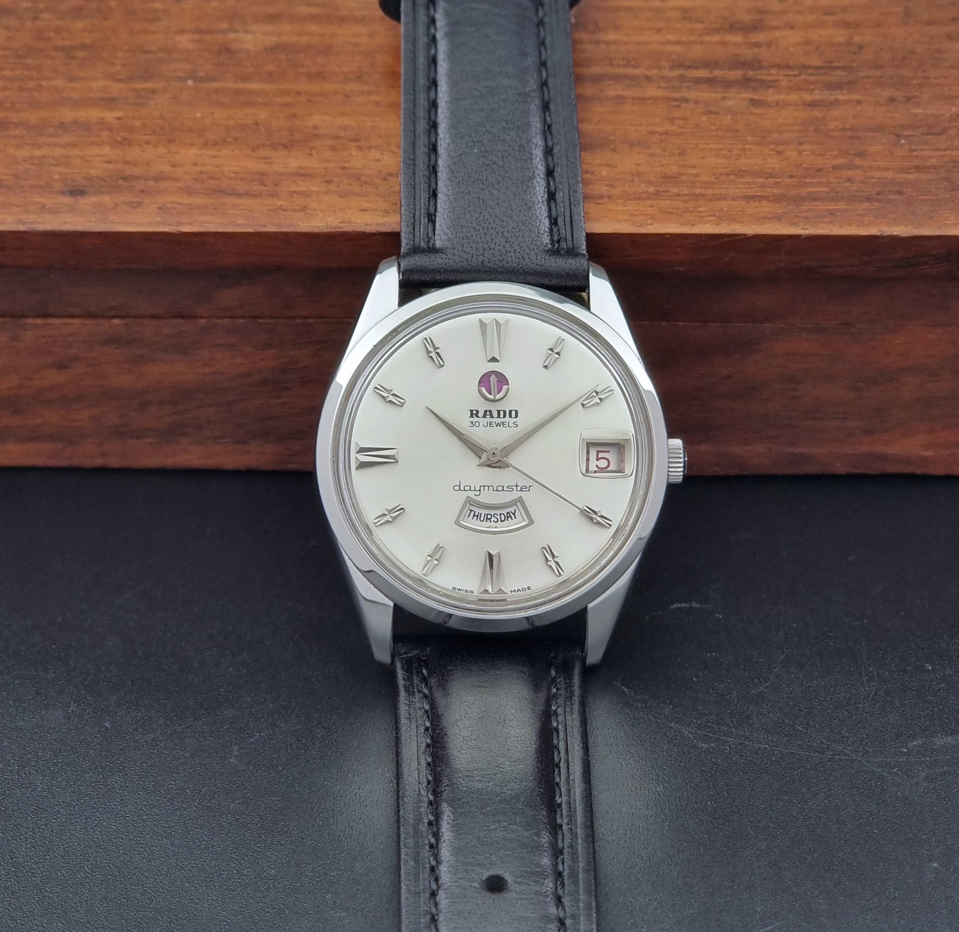 Vintage Rado wristwatch Daymaster 11754 with black leather strap on a dark surface dial view