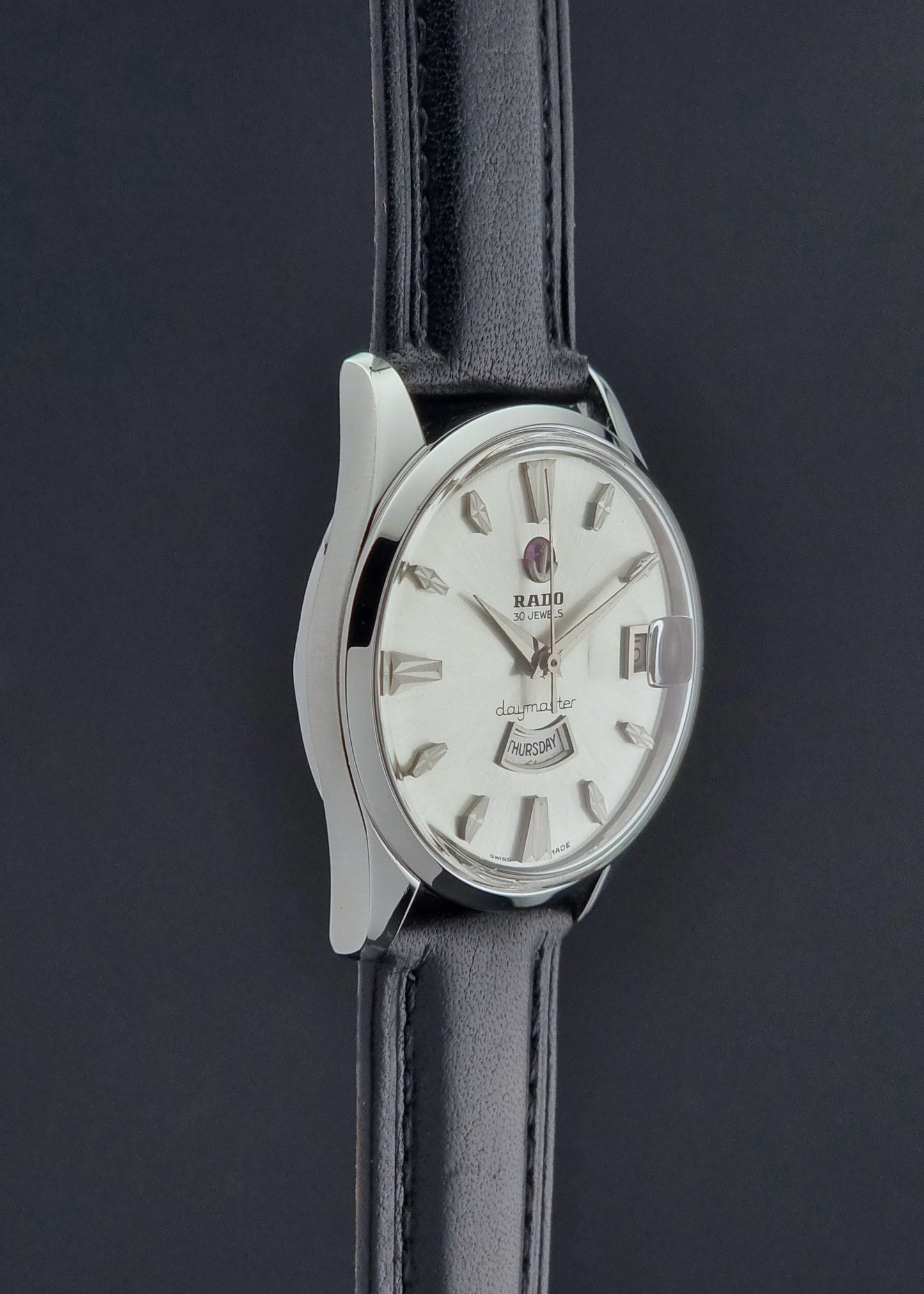 Vintage Rado wristwatch Daymaster 11754 with black leather strap on a dark surface side profile view