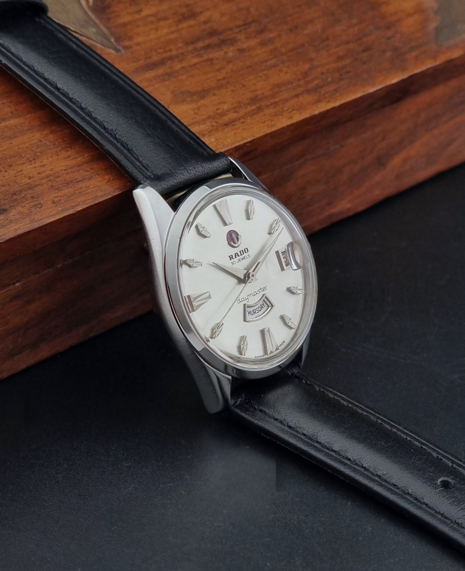 Vintage Rado wristwatch Daymaster 11754 with black leather strap on a dark surface side view