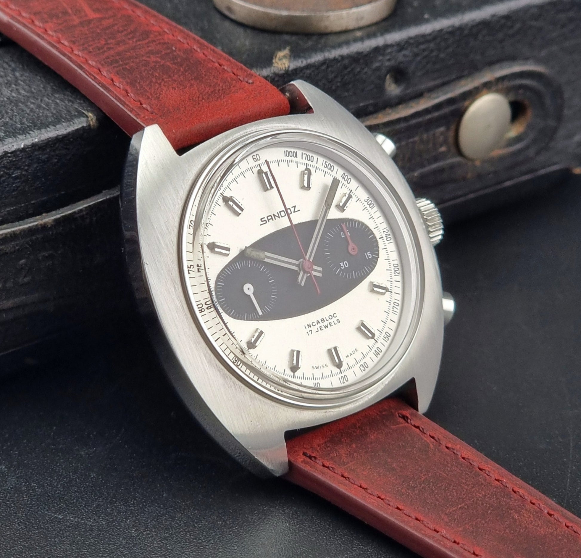 Vintage Sandoz watch watch with red leather strap on a dark textured background
