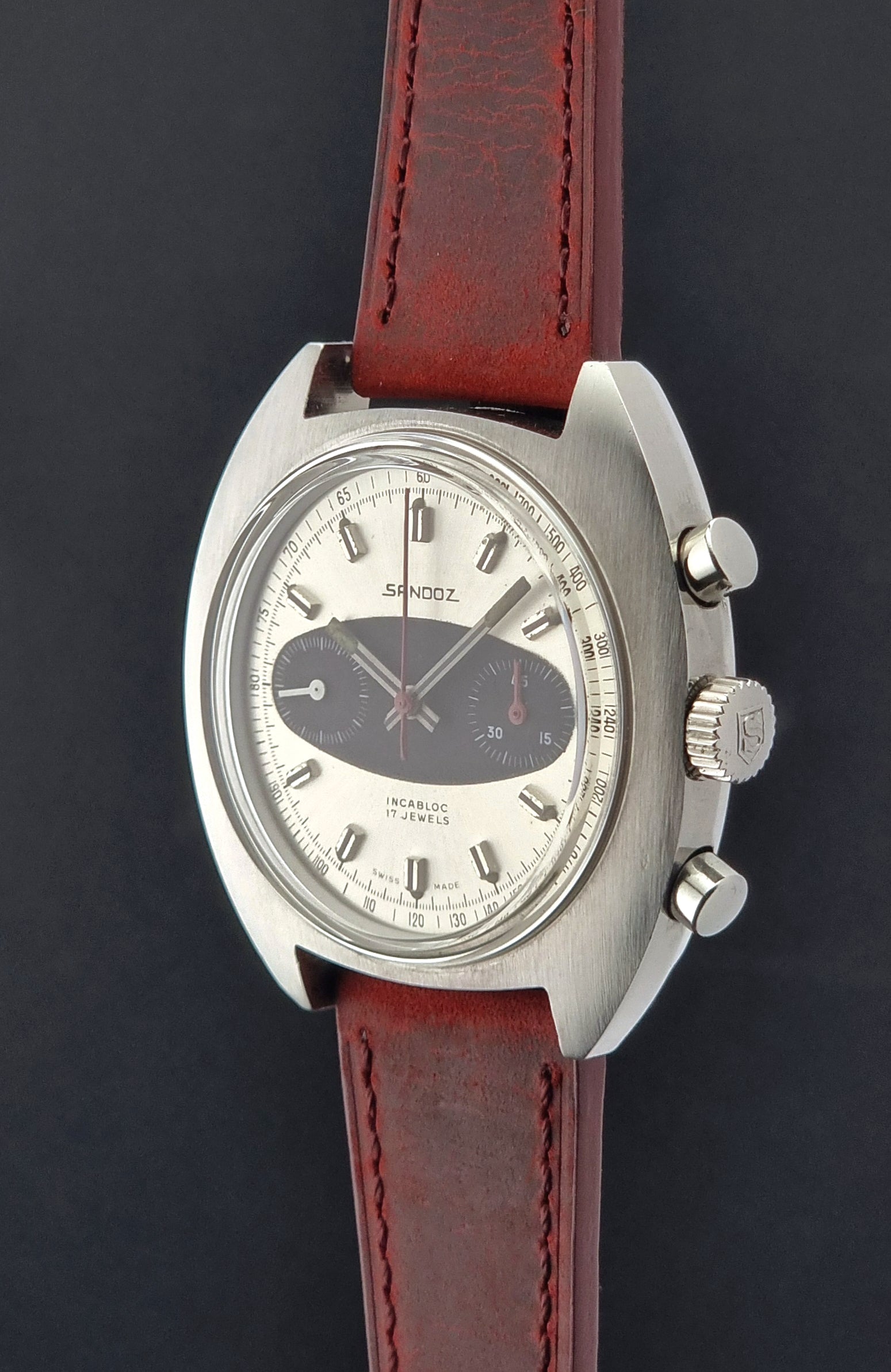 Wristwatch with red leather strap and silver case on a dark background