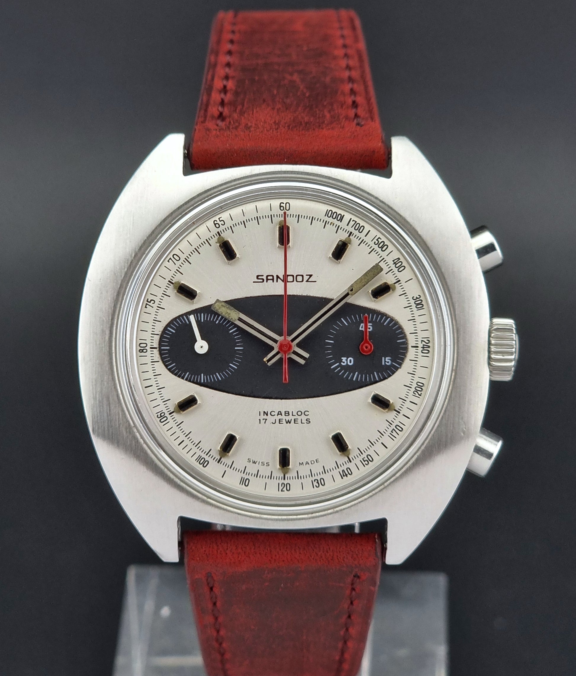 Vintage Sandoz wristwatch with red leather strap on a dark background