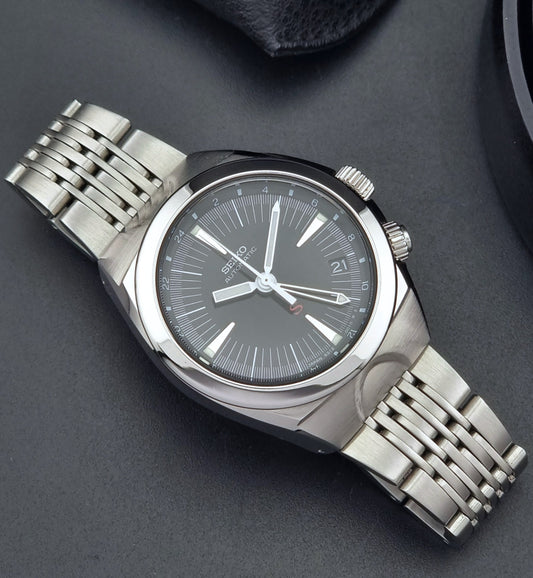 Seiko watch Mechasus SCFF005 GMT 4S12-0010 with a black face on a gray background front