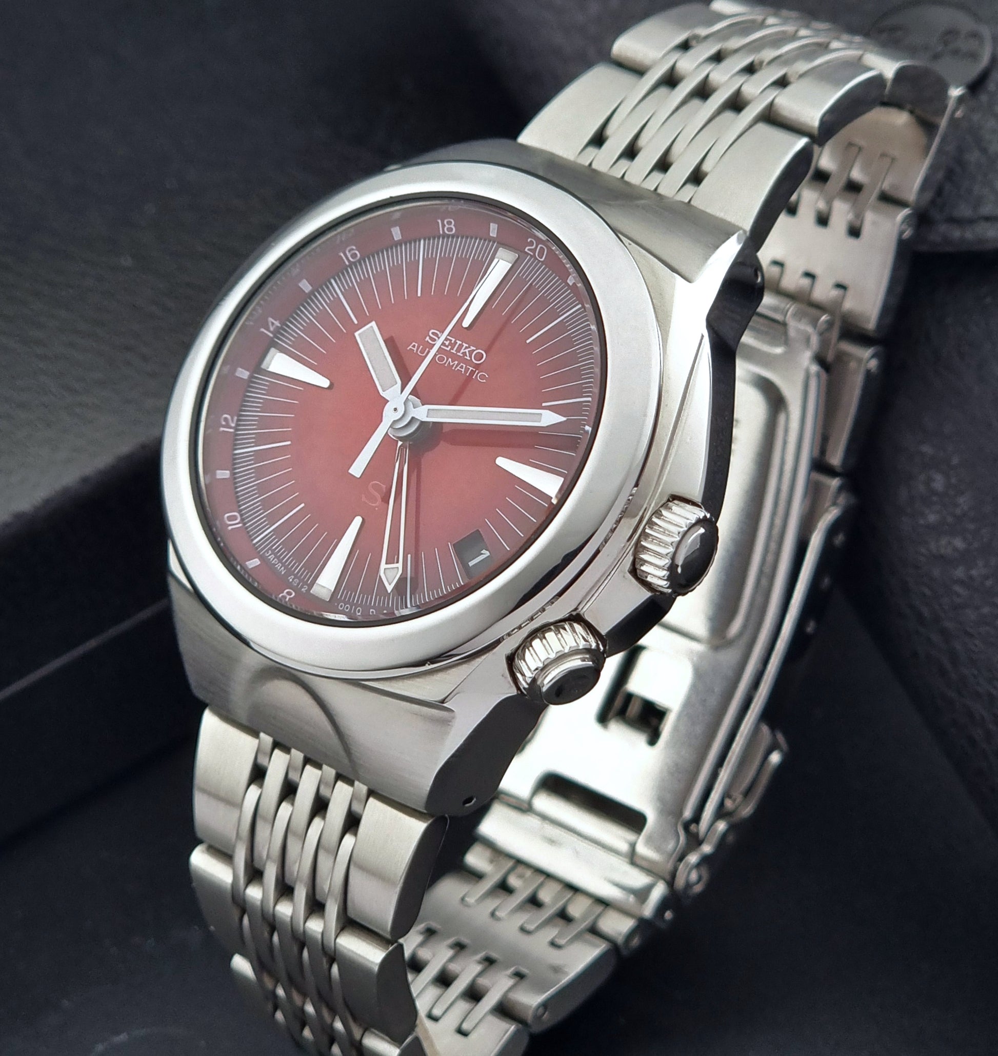 Seiko watch Mechasus SCFF007 GMT 4S12-0010 with a red face on a dark background crown view