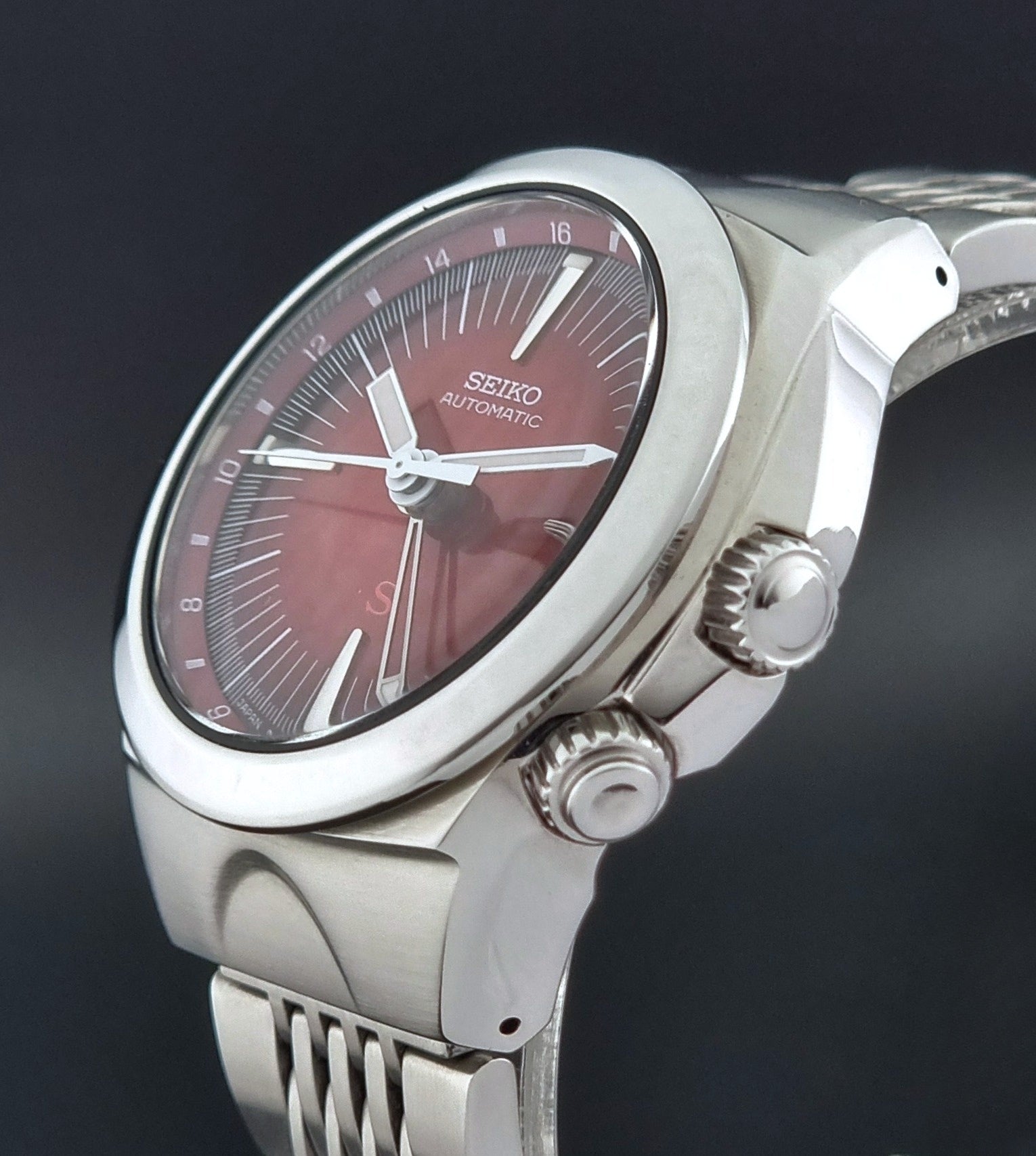 Seiko watch Mechasus SCFF007 GMT 4S12-0010 with a red face on a dark background crown profile view