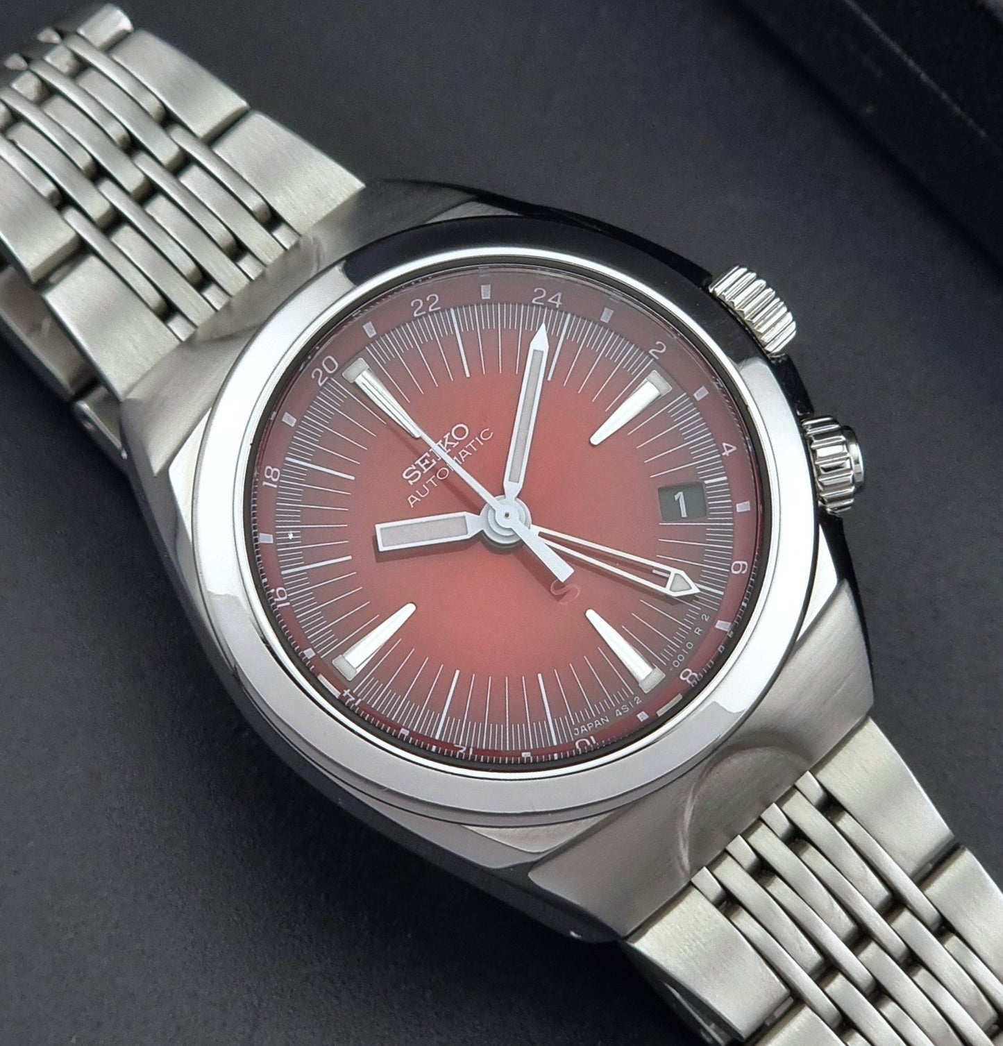 Seiko watch Mechasus SCFF007 GMT 4S12-0010 with a red face on a dark background dial view