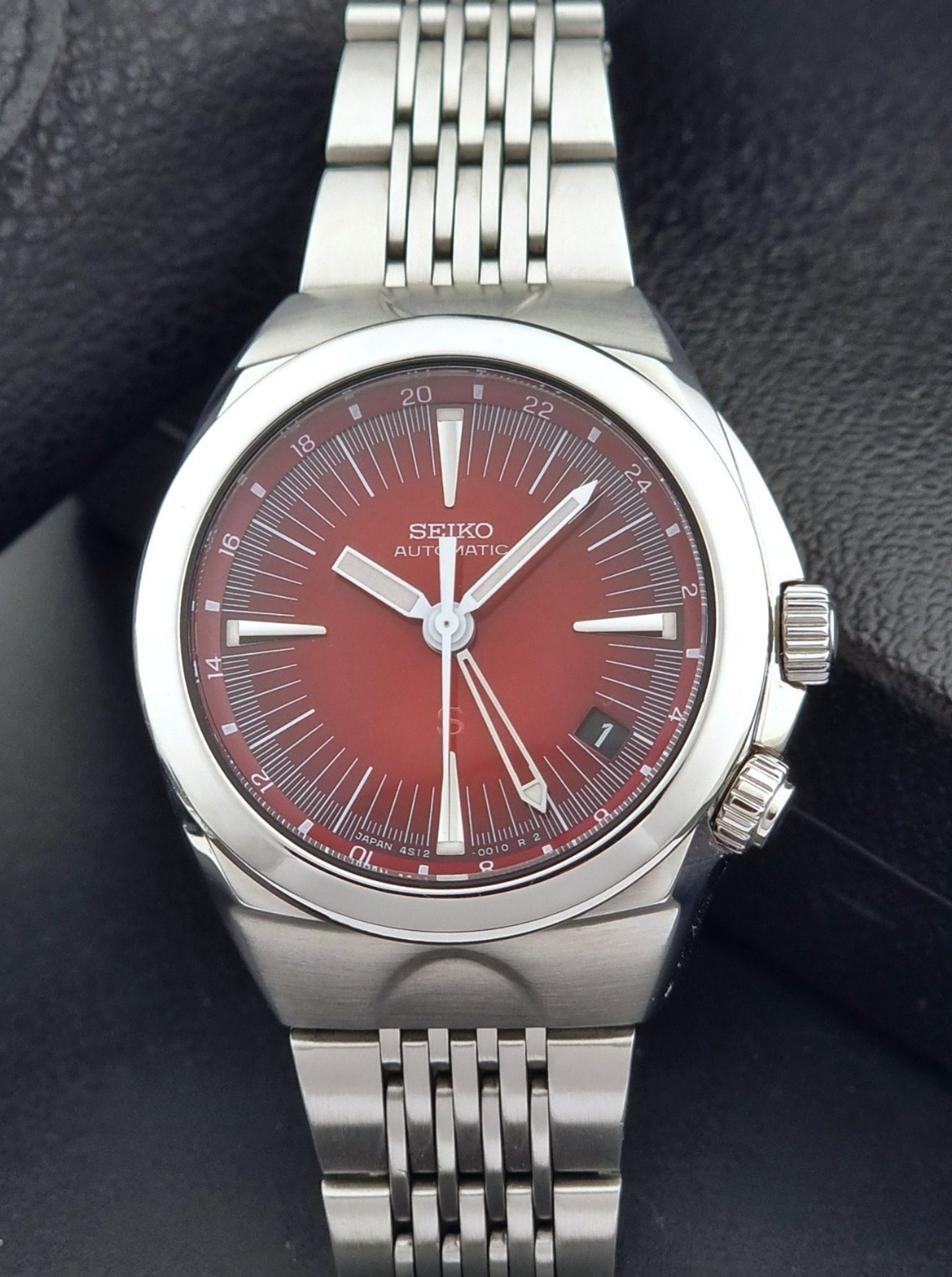 Seiko watch Mechasus SCFF007 GMT 4S12-0010 with a red face on a dark background close dial view