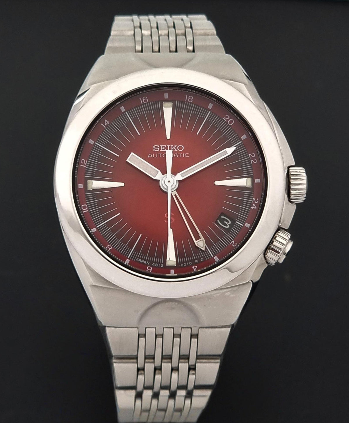 Seiko watch Mechasus SCFF007 GMT 4S12-0010 with a polished silver-tone metal case and integrated bracelet, featuring a deep red sunburst dial with silver-tone hands and markers.