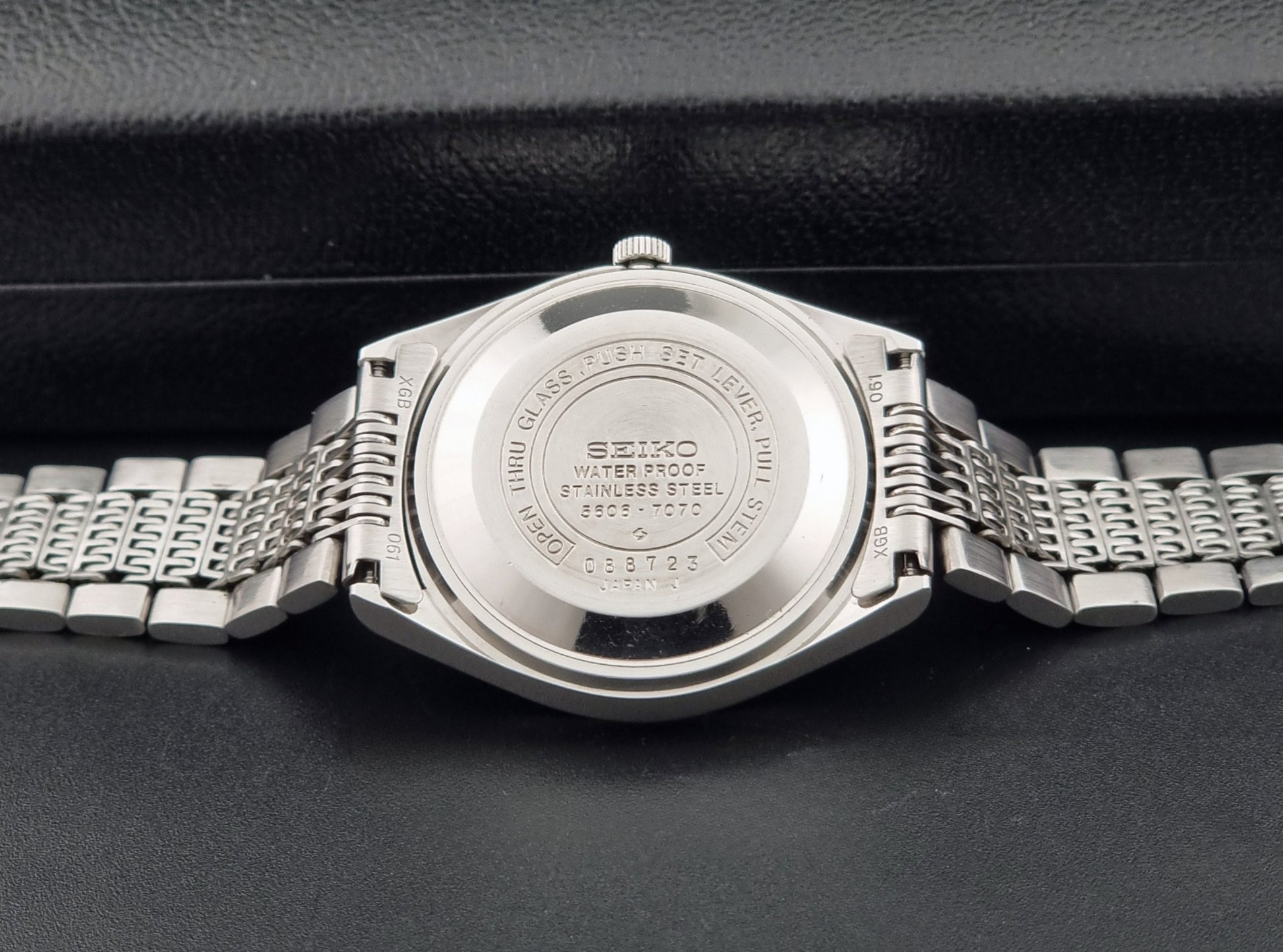 Vintage Seiko 5606-7070 LordMatic with a stainless steel bracelet on a dark background case back view