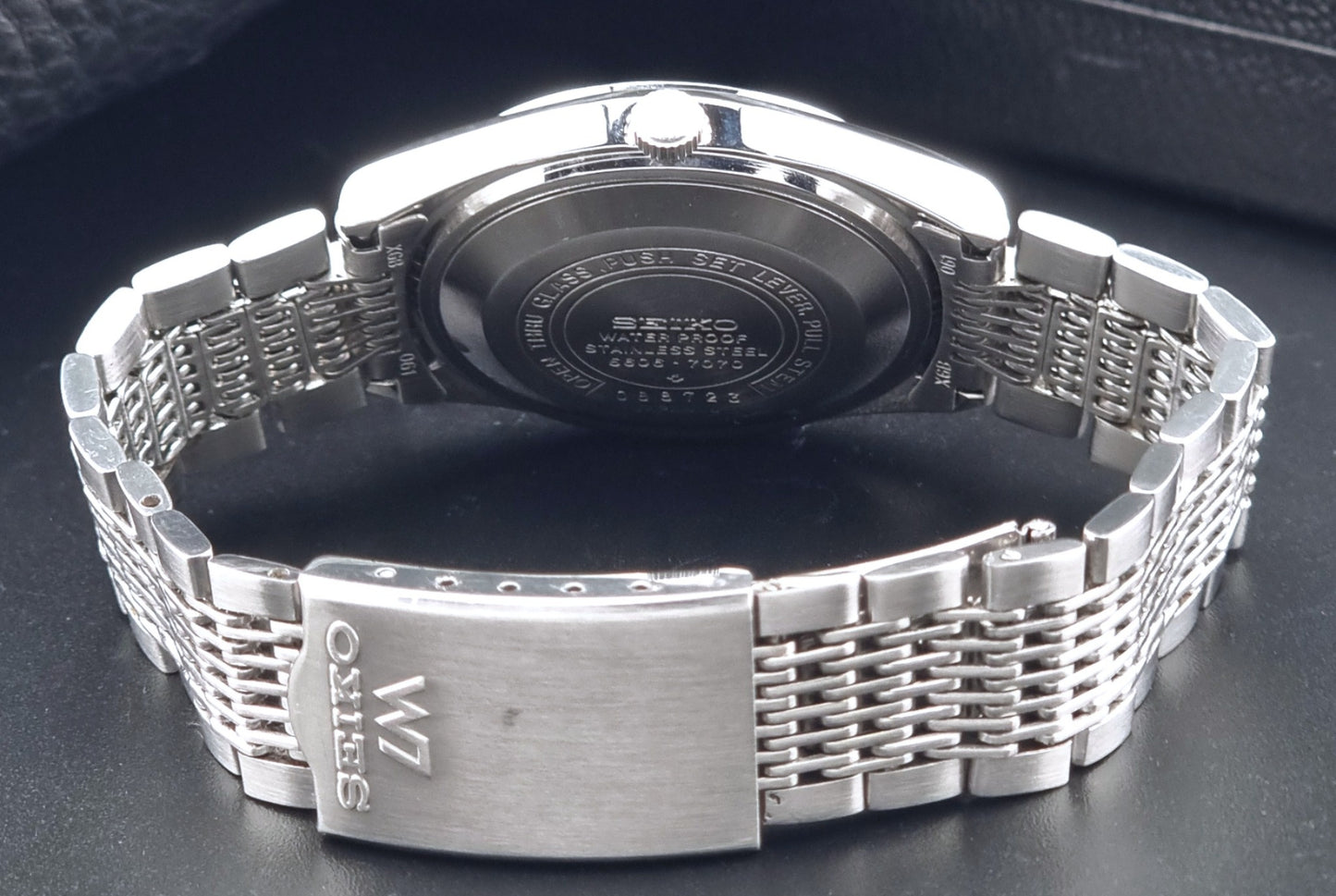 Vintage Seiko 5606-7070 LordMatic with a stainless steel bracelet on a dark background clasp view