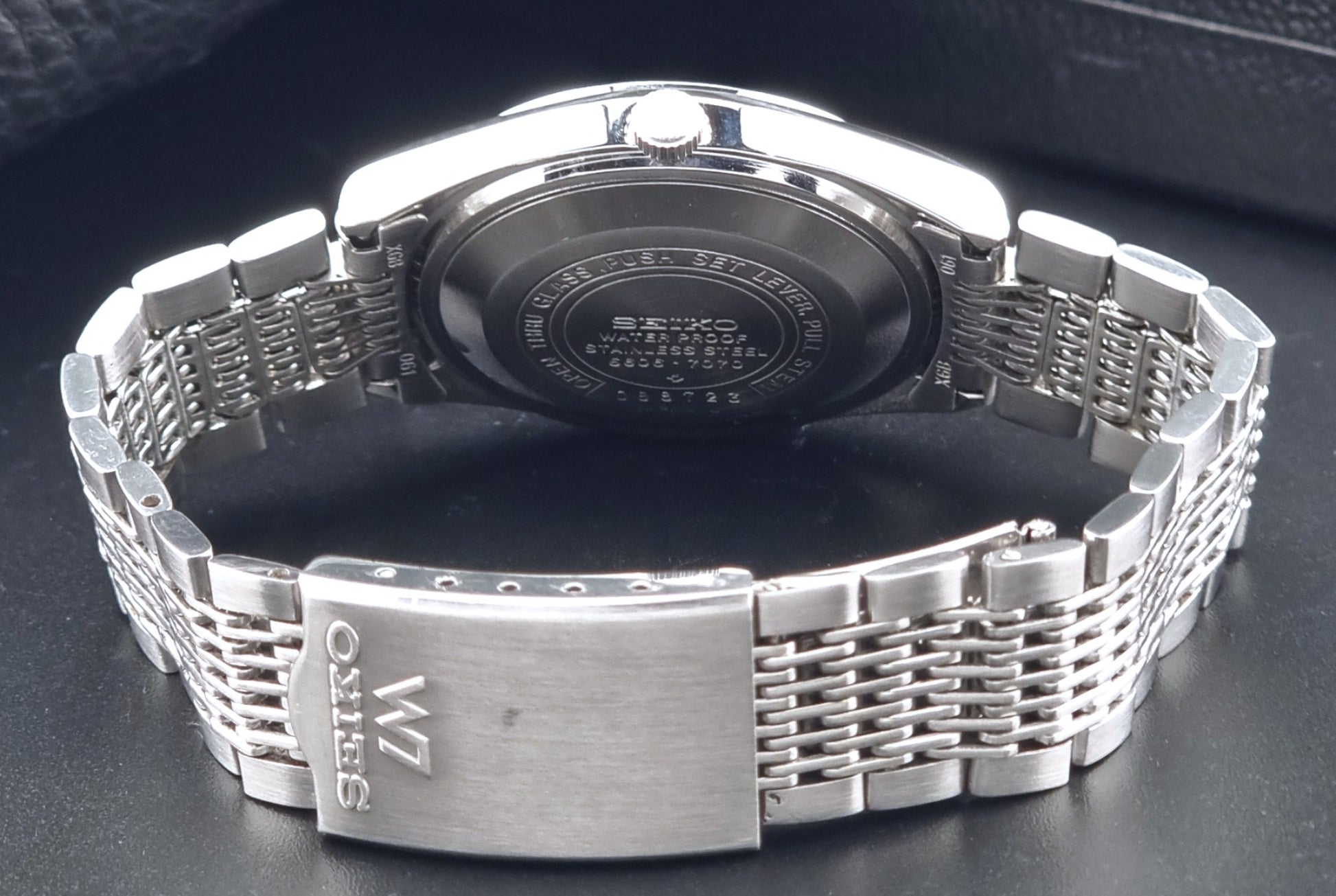 Vintage Seiko 5606-7070 LordMatic with a stainless steel bracelet on a dark background clasp view