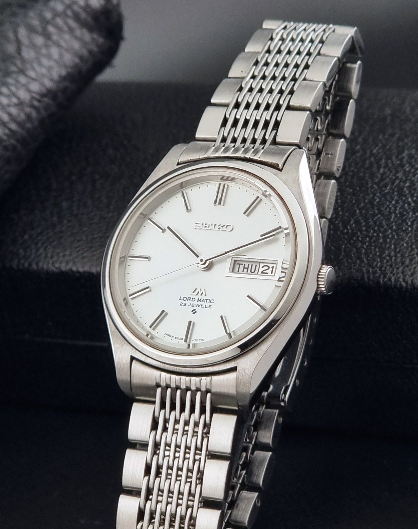 Vintage Seiko 5606-7070 LordMatic with a stainless steel bracelet on a dark background crown view