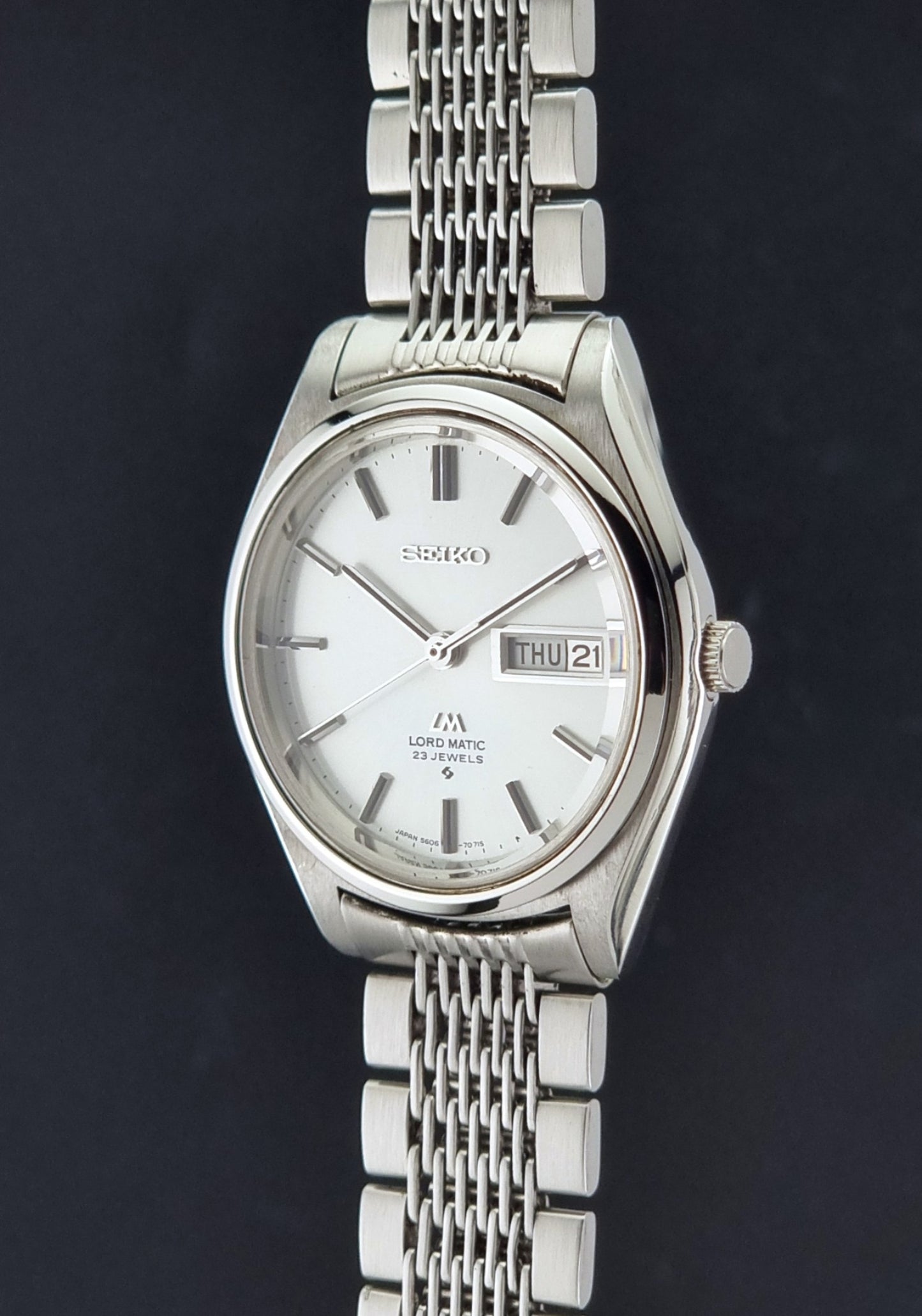 Vintage Seiko 5606-7070 LordMatic with a stainless steel bracelet on a dark background crown profile view