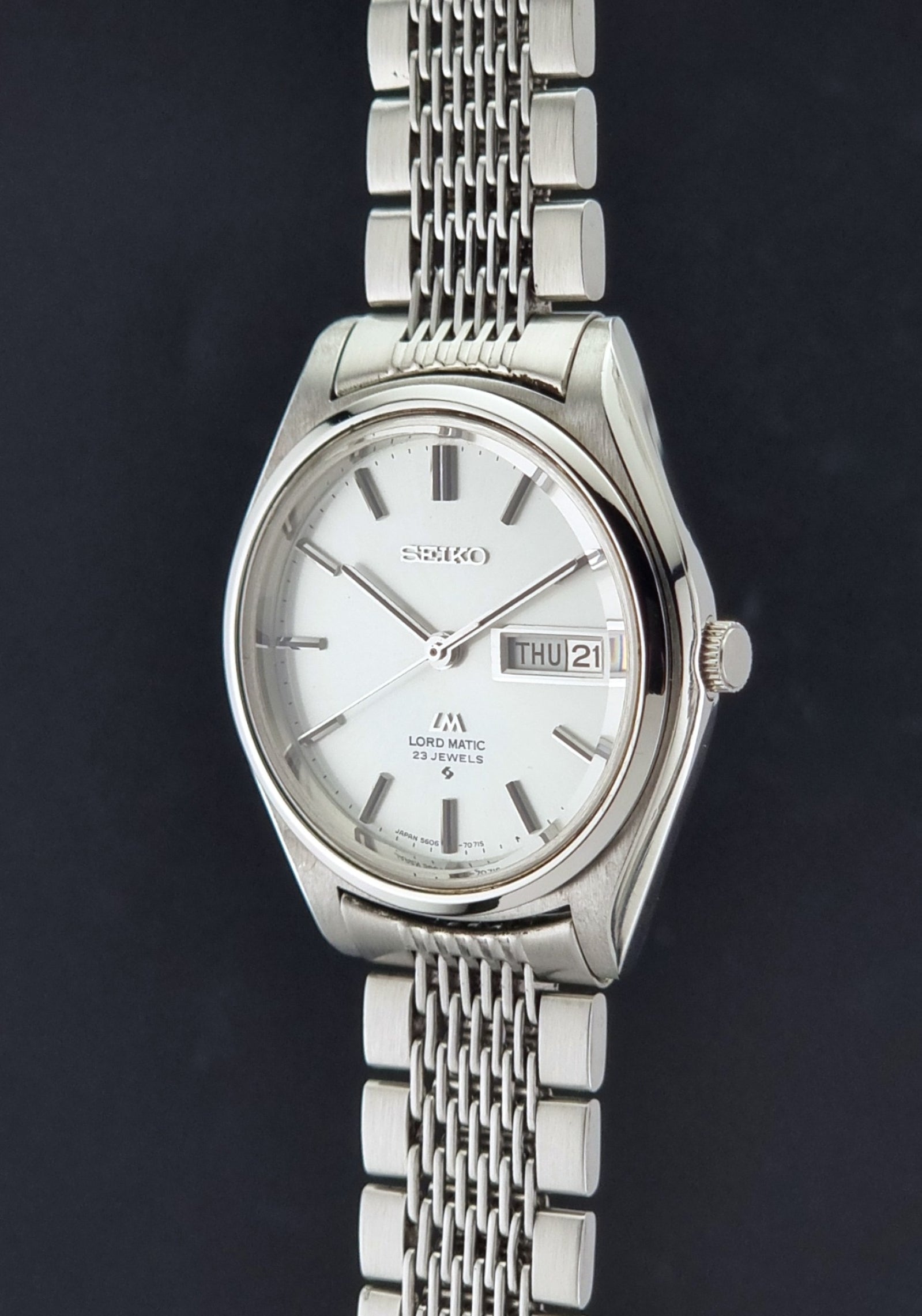 Vintage Seiko 5606-7070 LordMatic with a stainless steel bracelet on a dark background crown profile view