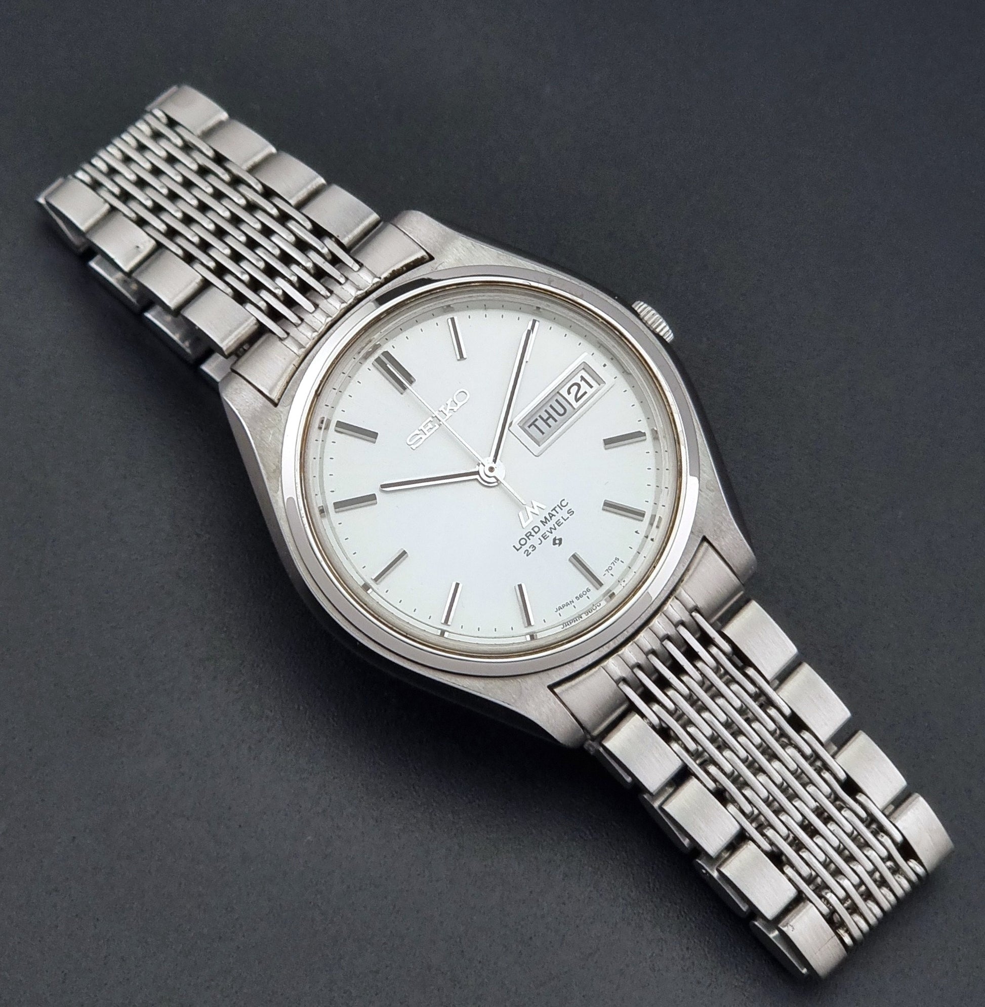 Vintage Seiko 5606-7070 LordMatic with a stainless steel bracelet on a dark background front