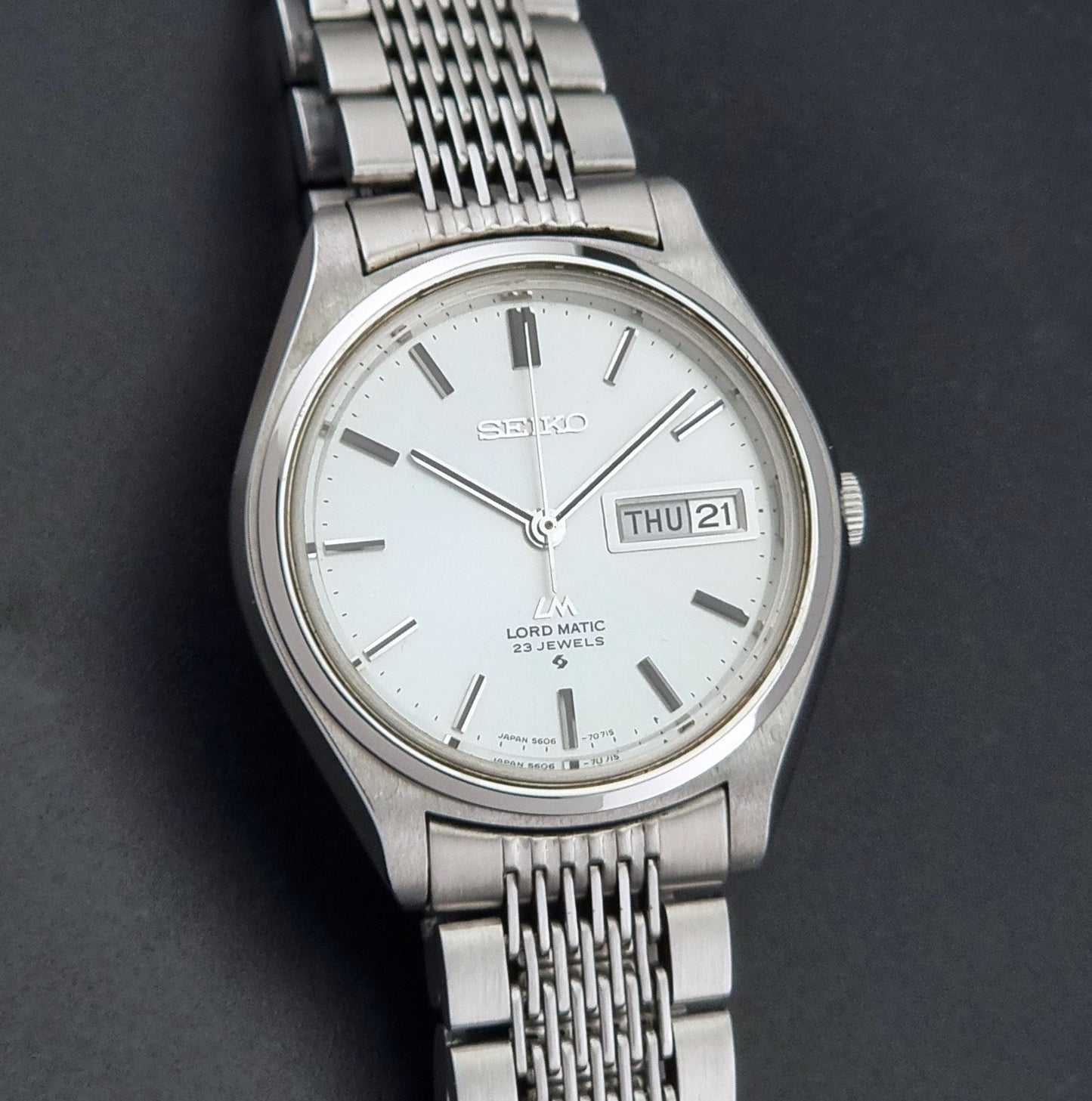 Vintage Seiko 5606-7070 LordMatic with a stainless steel bracelet on a dark background close dial view