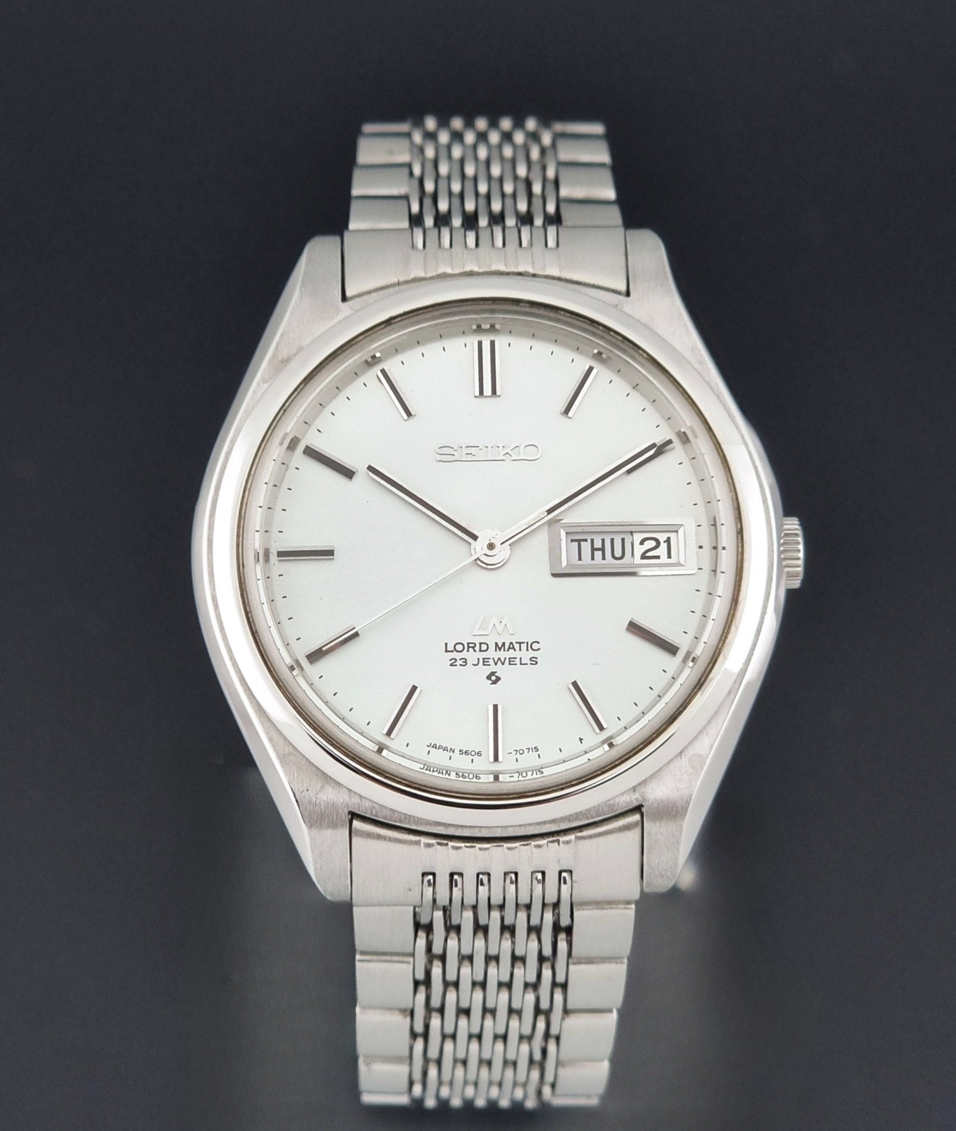 Vintage Seiko 5606-7070 LordMatic with a stainless steel bracelet on a dark background close dial view