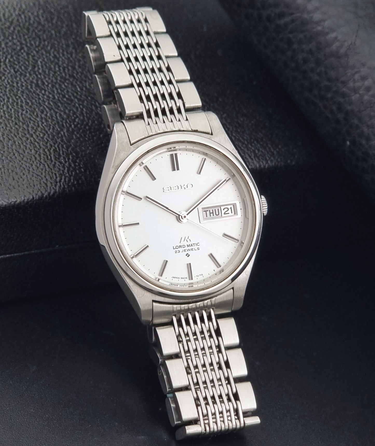Vintage Seiko 5606-7070 LordMatic with a stainless steel bracelet on a dark background side view