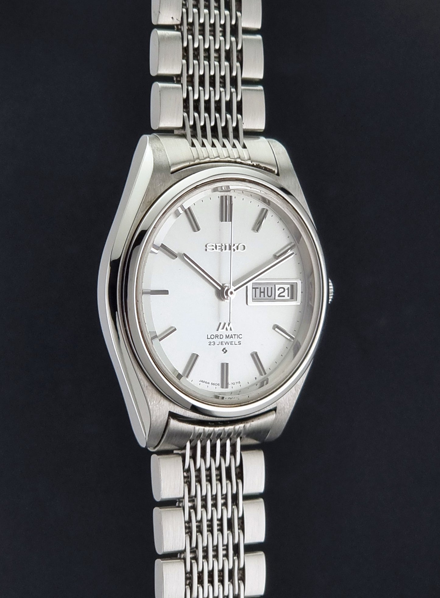 Vintage Seiko 5606-7070 LordMatic with a stainless steel bracelet on a dark background side profile view