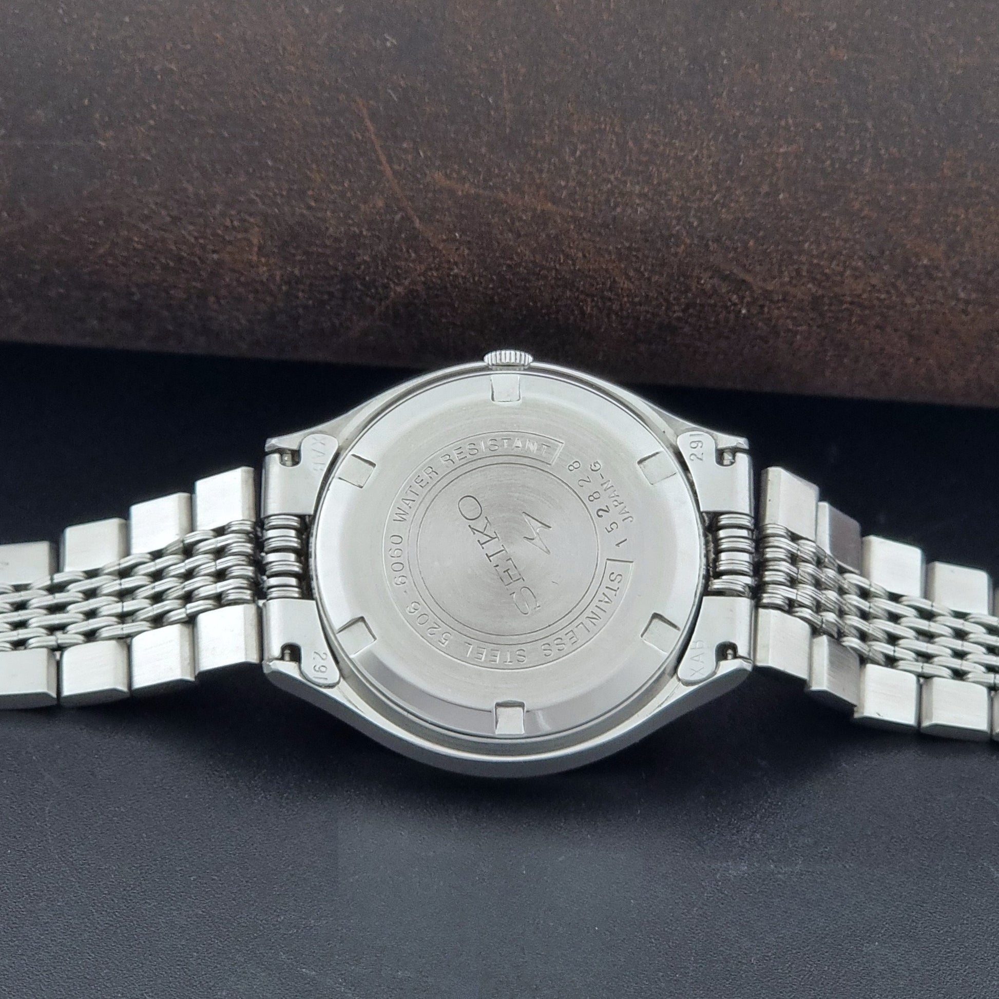Vintage Seiko watch LordMatic Special 5206-6060 with a white face on a dark gray background case back view