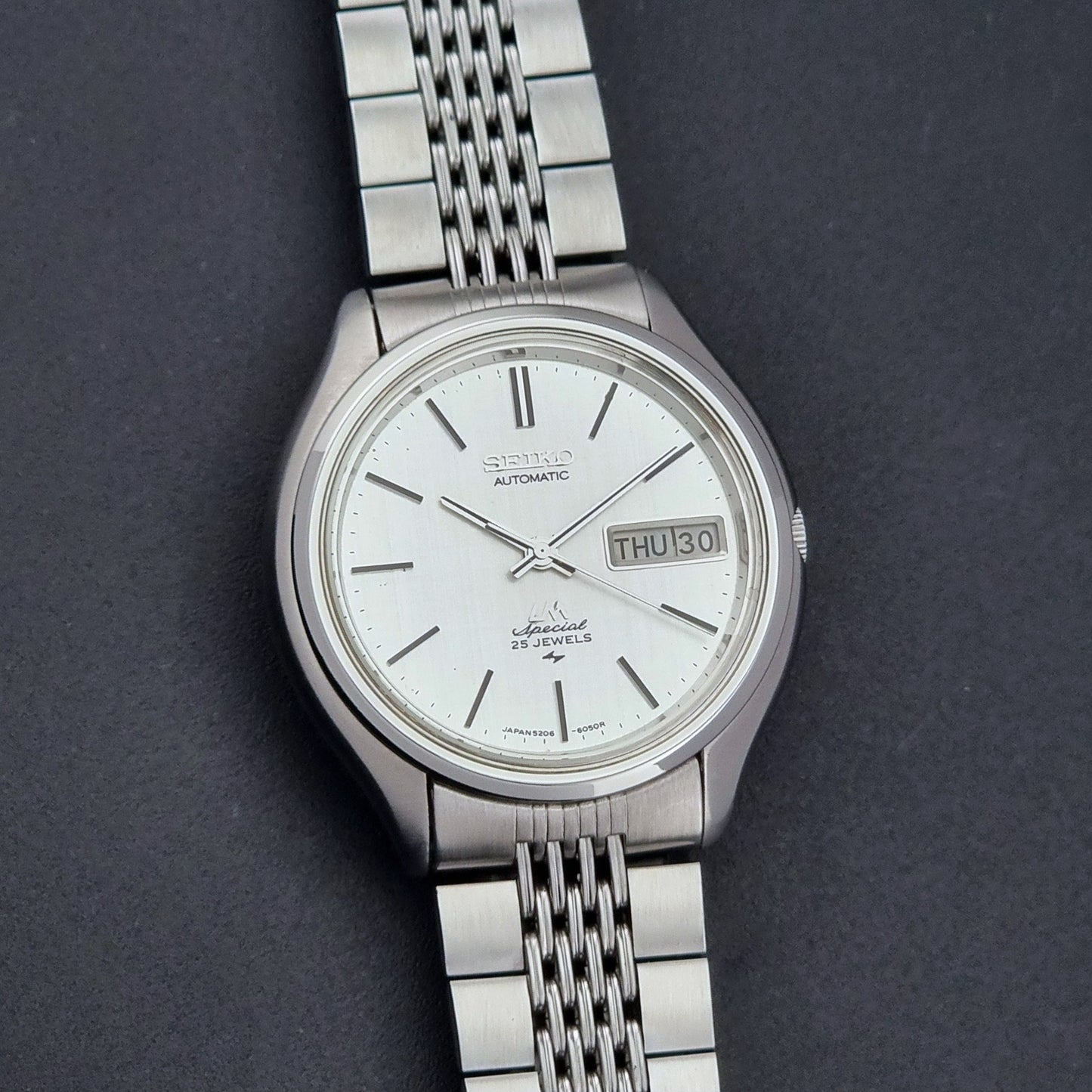 Vintage Seiko watch LordMatic Special 5206-6060 with a white face on a dark gray background close up dial view