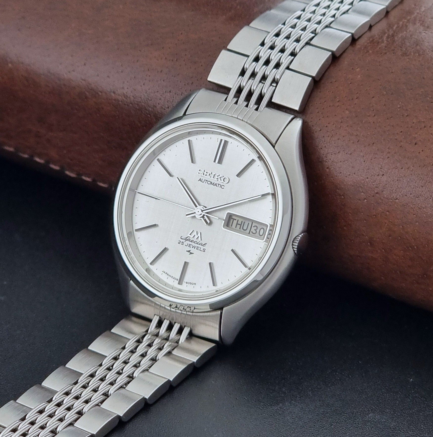 Vintage Seiko watch LordMatic Special 5206-6060 with a white face on a dark gray background crown view