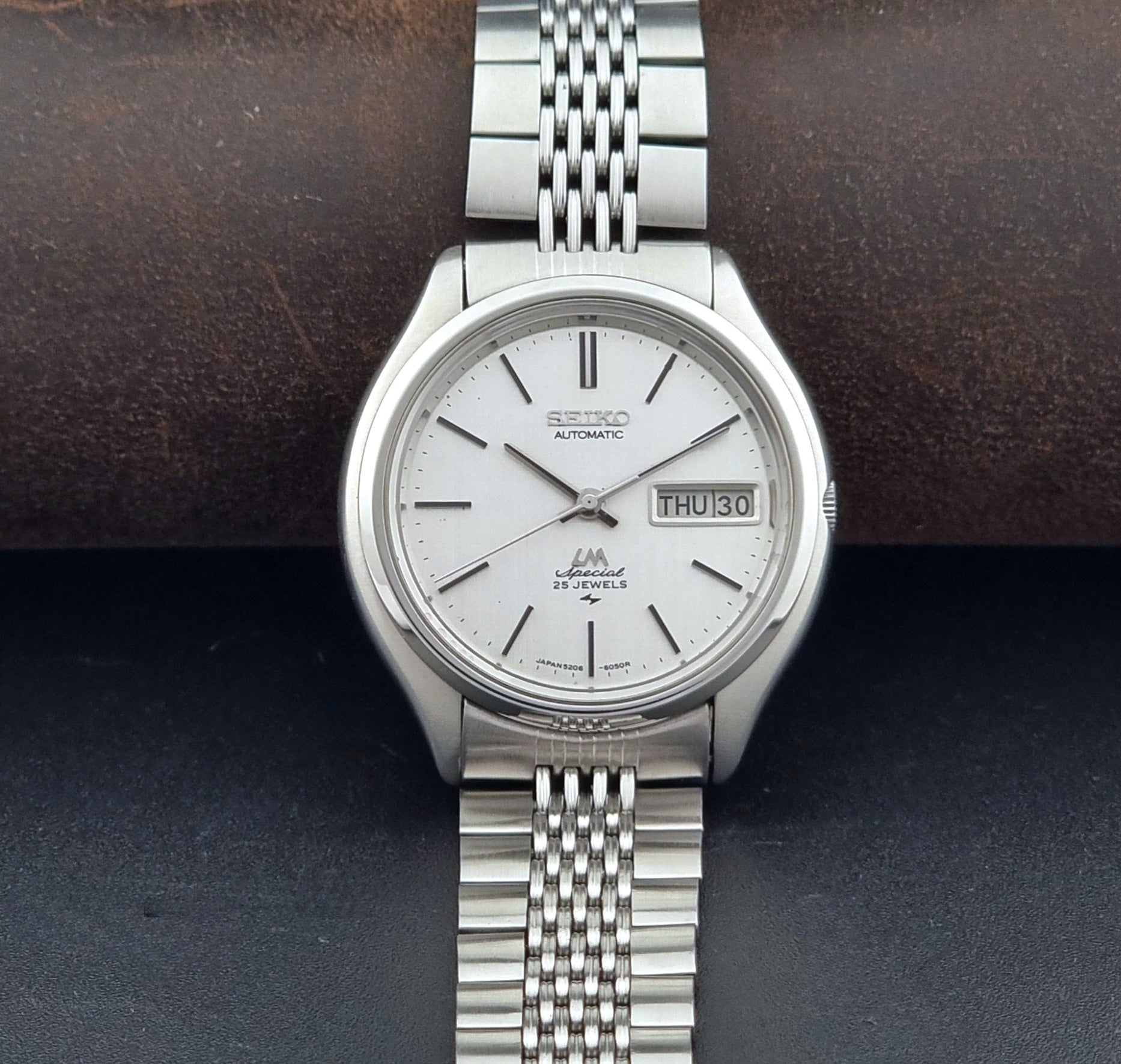 Vintage Seiko watch LordMatic Special 5206-6060 with a white face on a dark gray background dial view