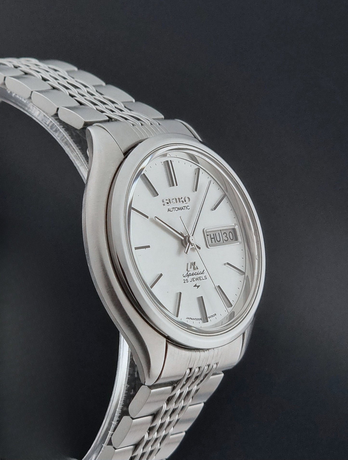 Vintage Seiko watch LordMatic Special 5206-6060 with a white face on a dark gray background side profile view