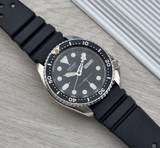 Black Seiko Quartz Dive watch 7548-7000 with a detailed face on a light wooden surface