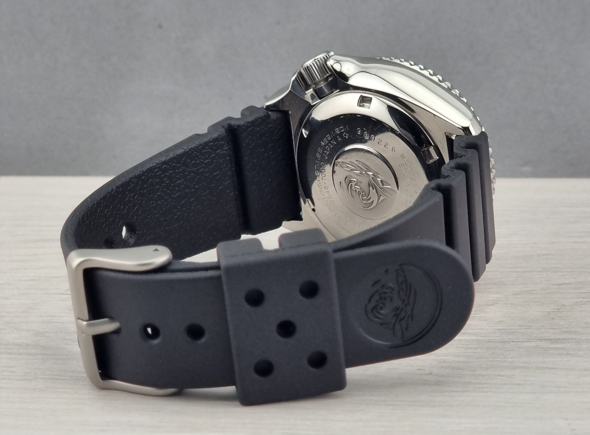 Close-up of a watch with a black strap on a wooden surface