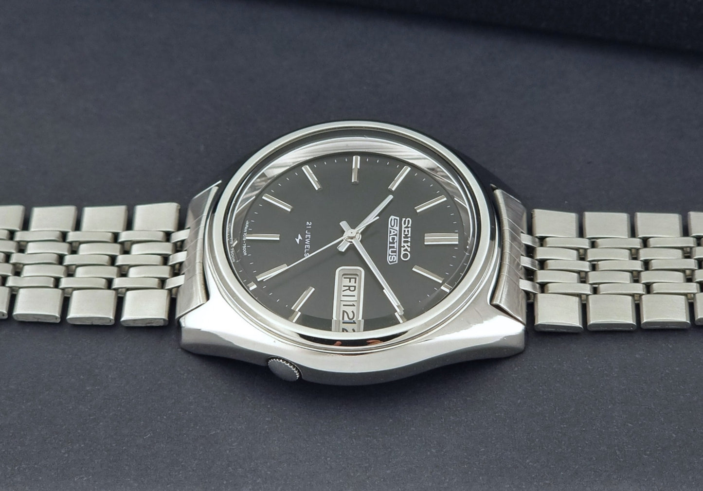 Vintage Seiko 5 Actus Wristwatch 7019-7060 with a stainless steel bracelet on a dark surface crown profile view