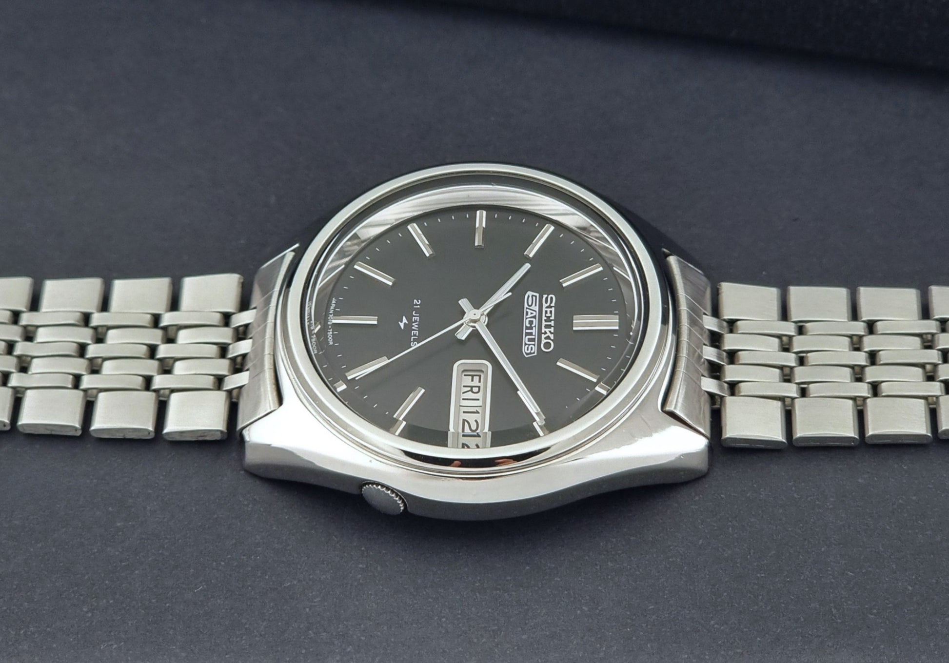 Vintage Seiko 5 Actus Wristwatch 7019-7060 with a stainless steel bracelet on a dark surface crown profile view